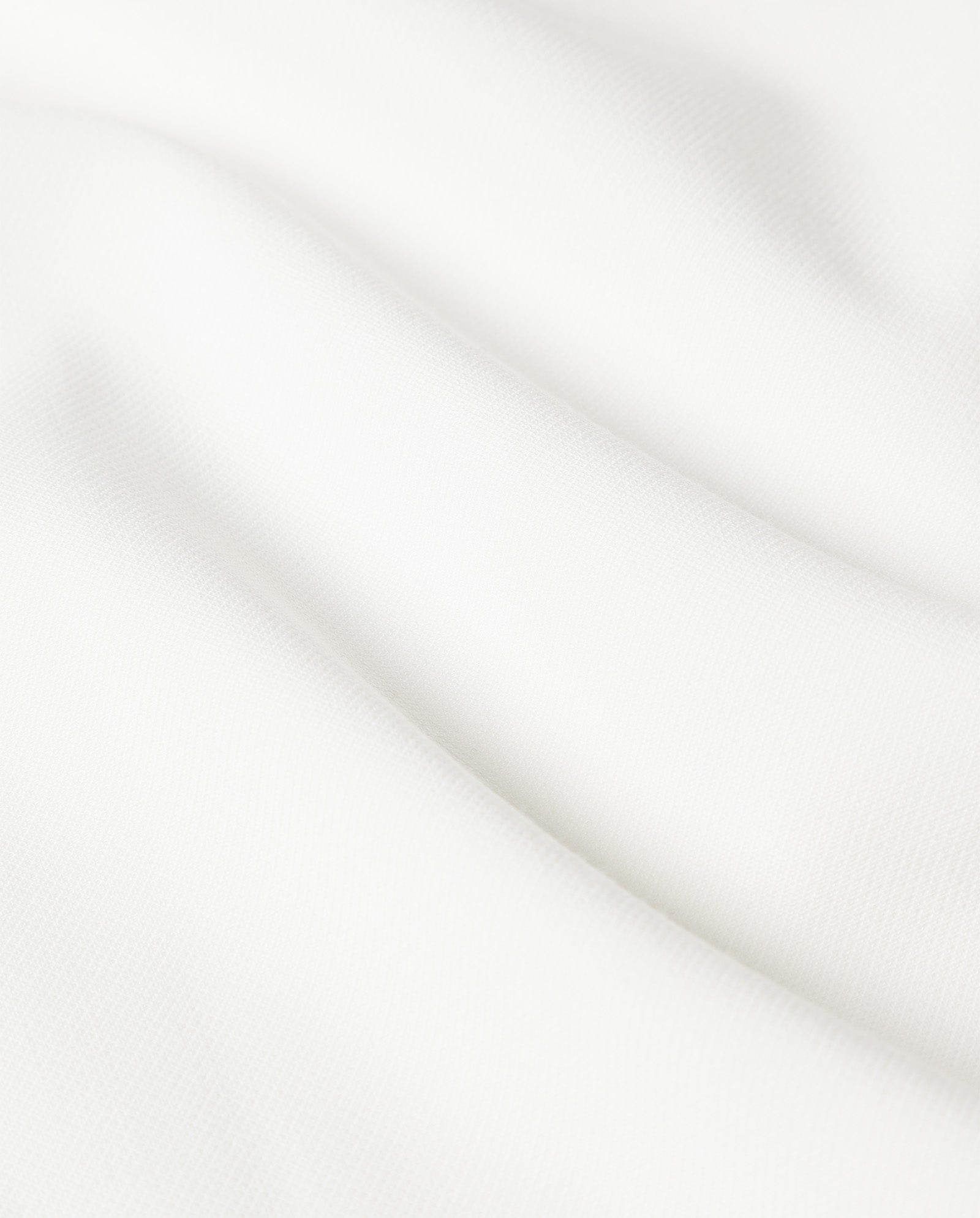 Close-up of the smooth, white fabric used for the IVY OAK NOLAN Dress, featuring gentle folds and a subtle textured surface—ideal for an elegant ankle-length look.
