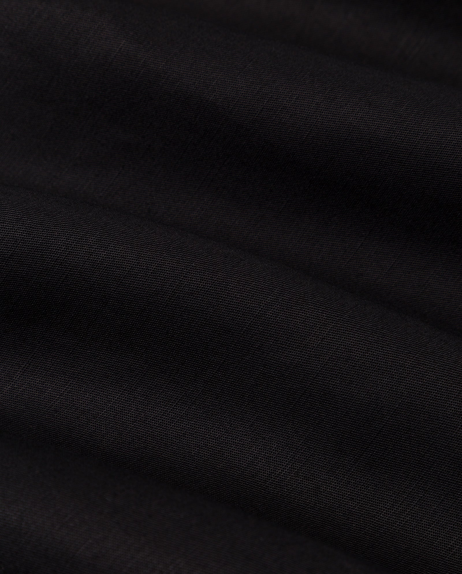 Close-up of the black linen blend fabric of the IVY OAK NELA Dress, featuring soft horizontal folds and a smooth, matte texture.
