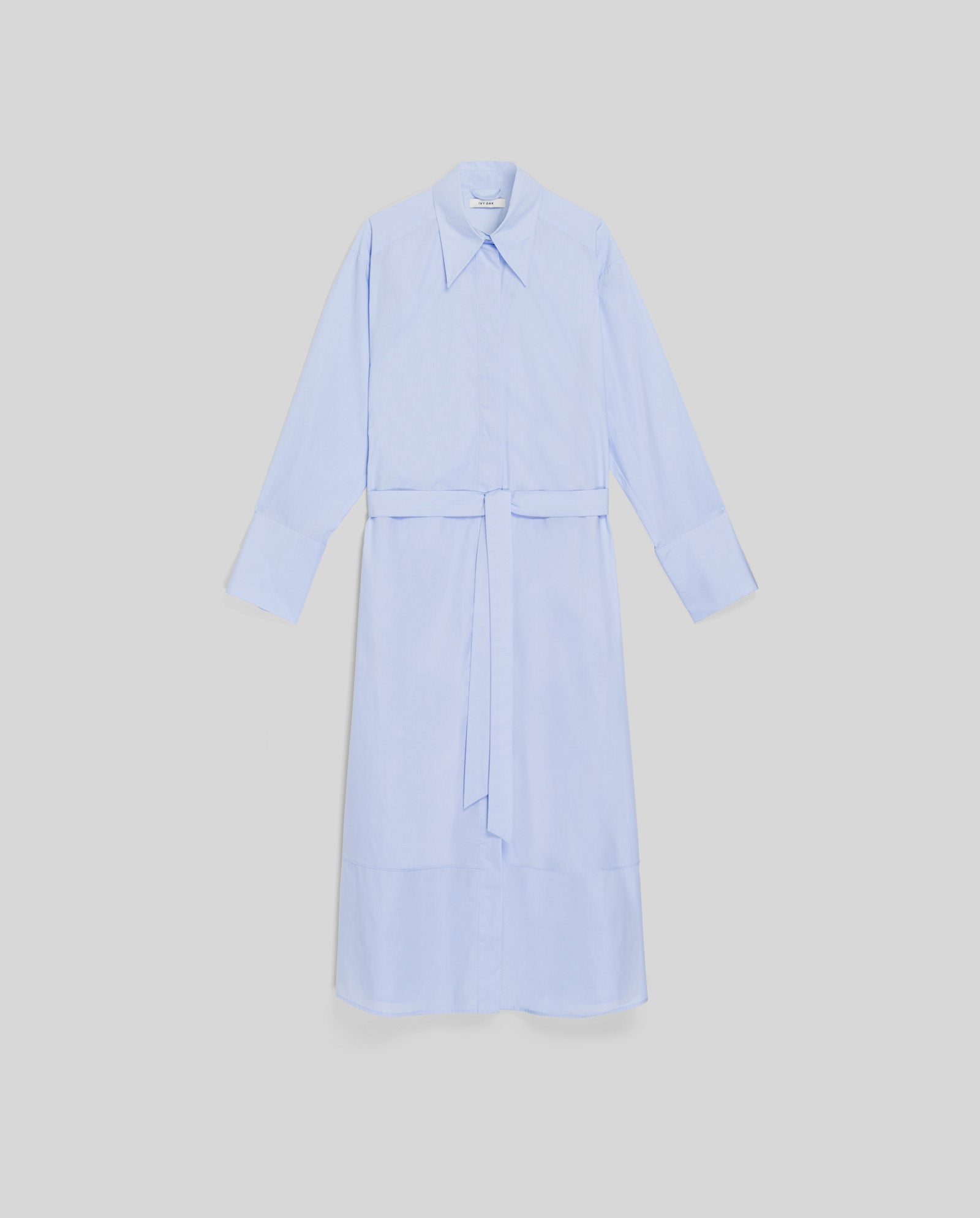 The DINA ROSA Dress by IVY OAK is a light blue cotton summer shirt dress with a collar, matching fabric belt, and adjustable cuffs, shown on a plain background.