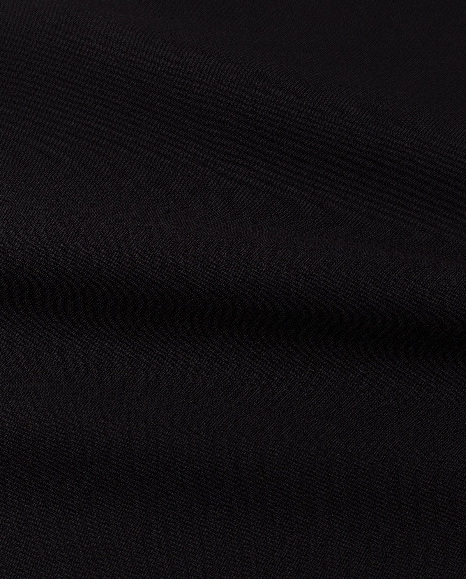 A close-up of the NEPHELIA Dress by IVY OAK highlights its matte plain black fabric, featuring subtle folds and a soft texture.