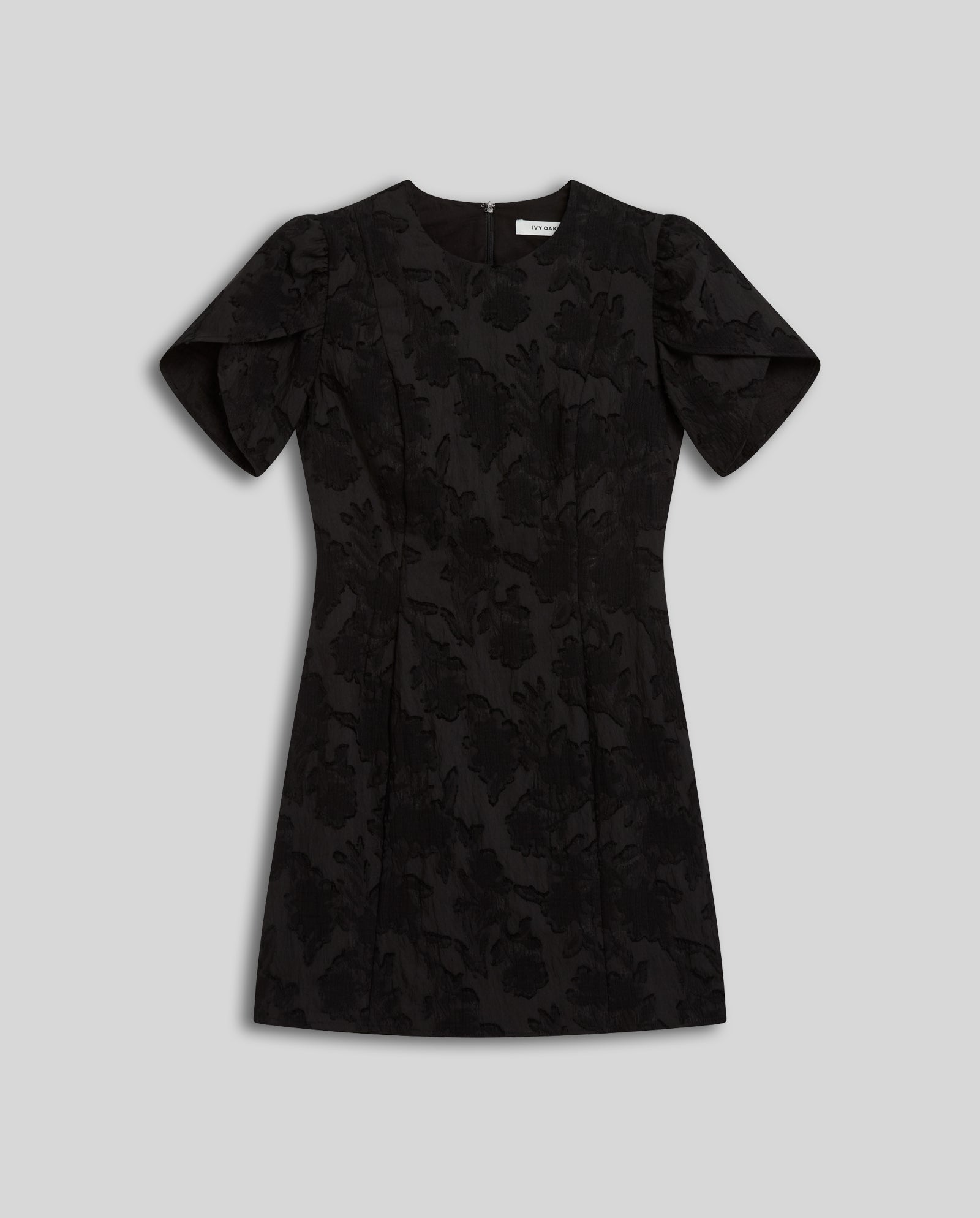 The IVY OAK NERISSA Dress is a short black fil coupé mini dress with floral-patterned fabric and short puffed sleeves, shown flat on a light gray background.