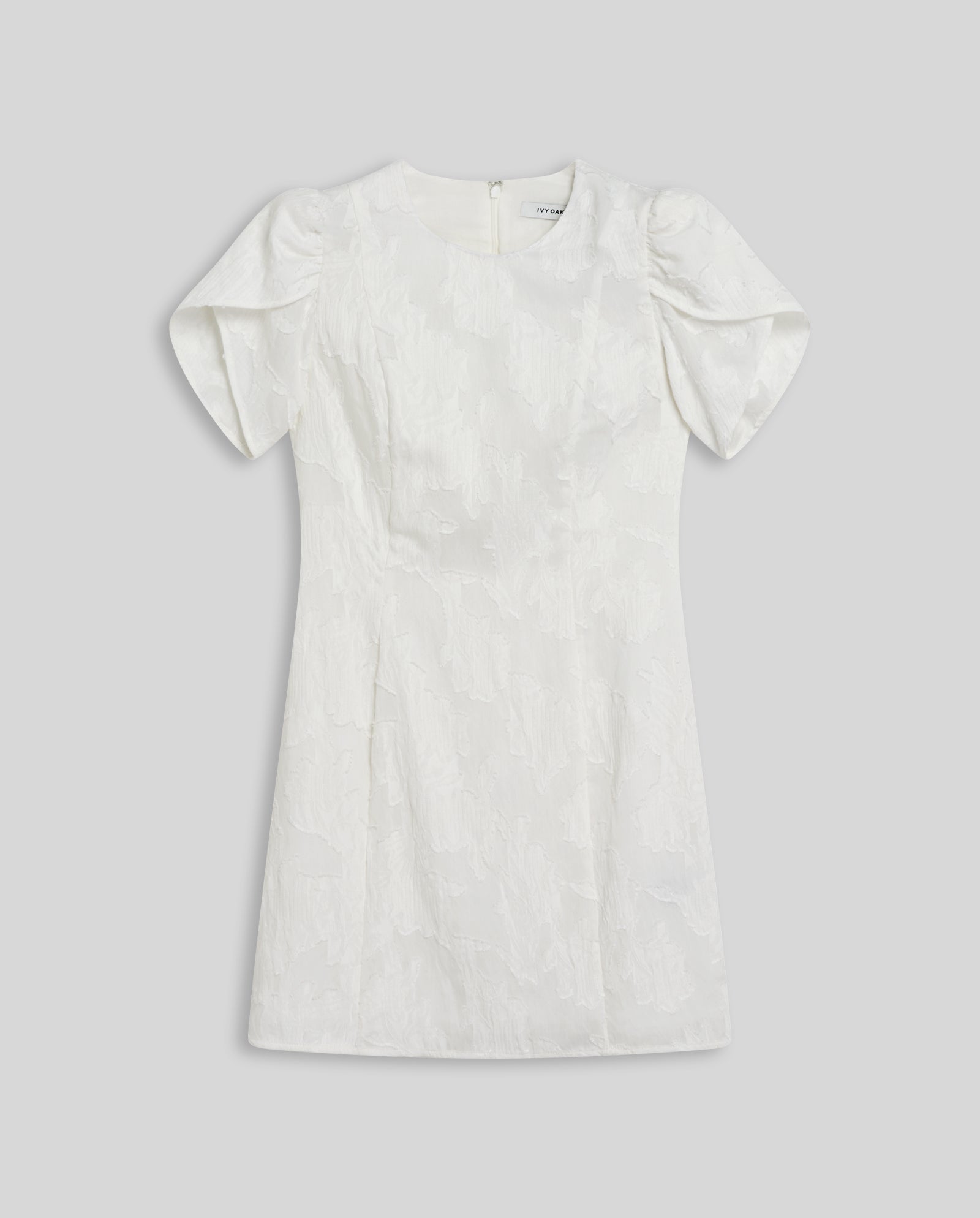 The IVY OAK NERISSA Dress is a short white fil coupé mini dress with puffed floral sleeves, a textured floral pattern, and a round neckline, displayed flat on a gray background.