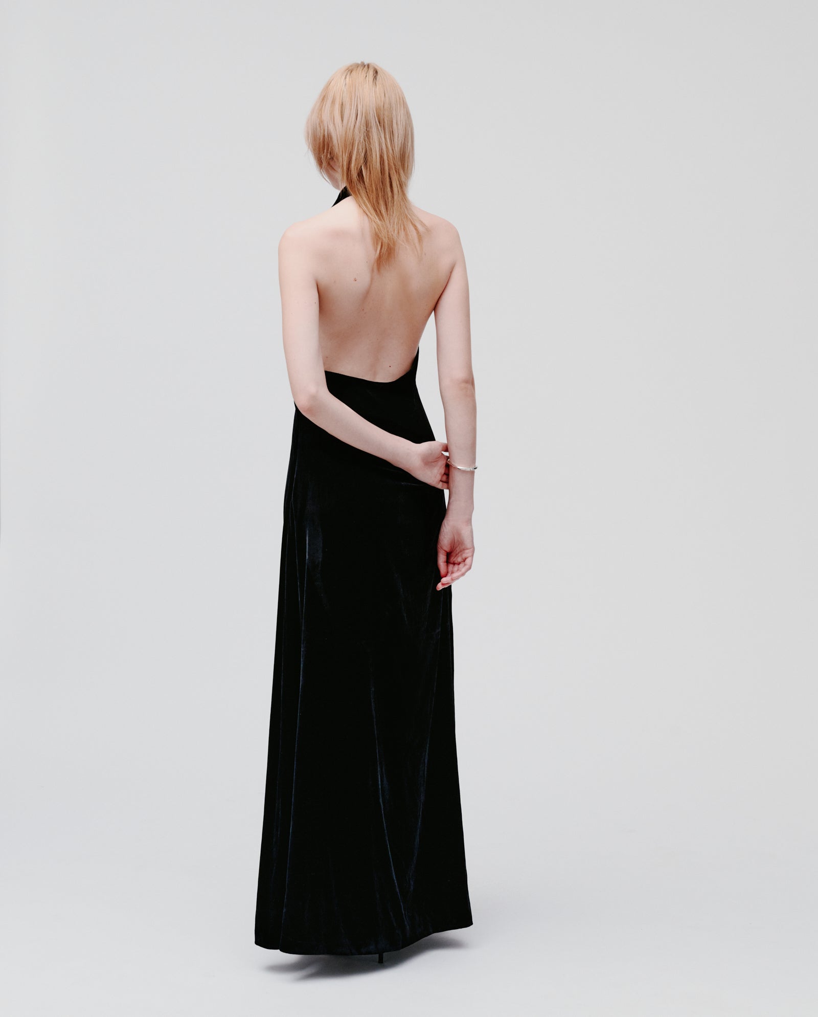 A woman wearing the IVY OAK NESTA ROSE long, strapless black velvet midi dress stands facing away against a plain light background.