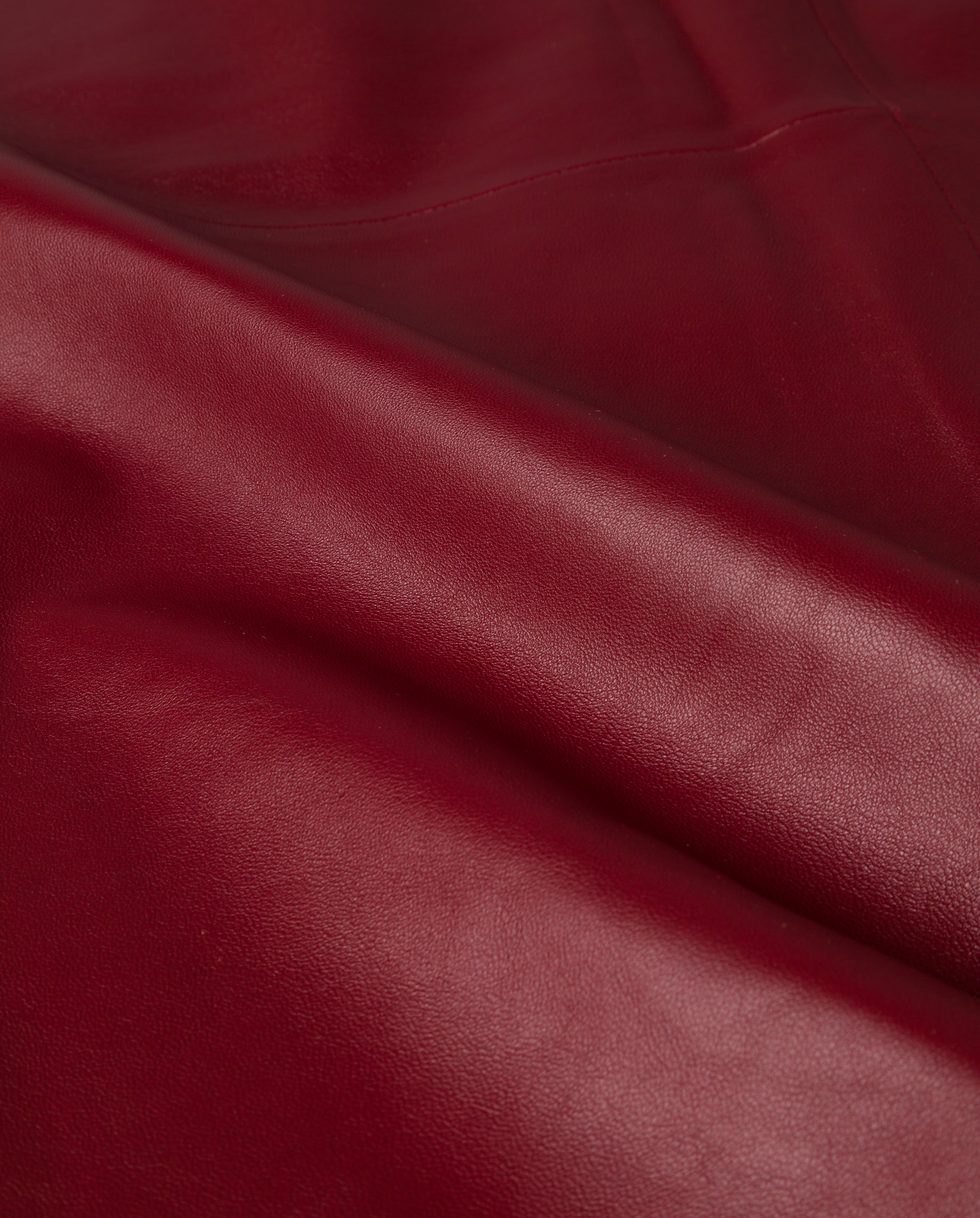 A close-up of smooth red leather with gentle folds and a soft sheen, perfect for crafting the chic LEXIE Skirt by IVY OAK.