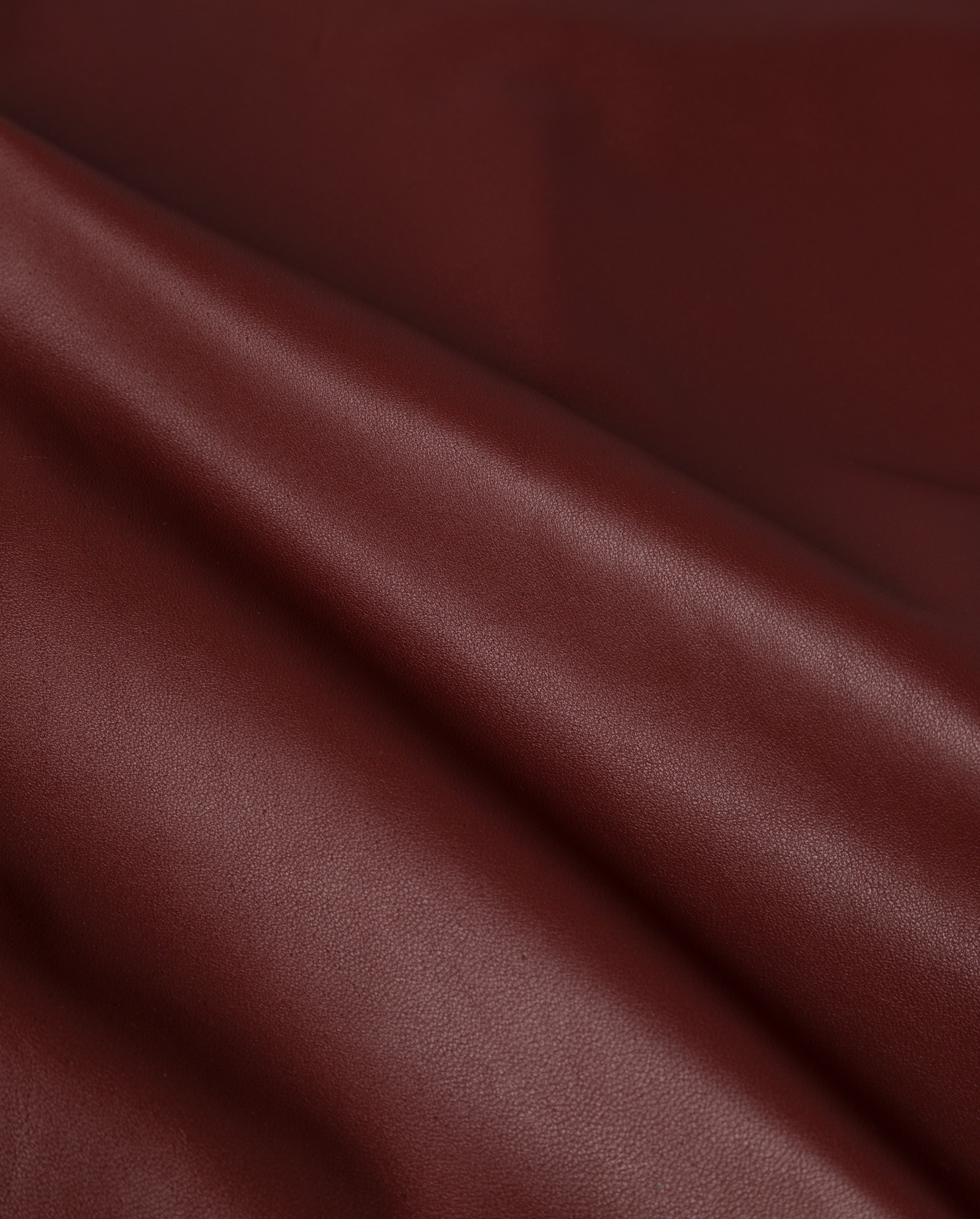Close-up of smooth, rich brown leather fabric with gentle folds and a soft sheen—ideal for crafting the modern LORAINE Trouser by IVY OAK.