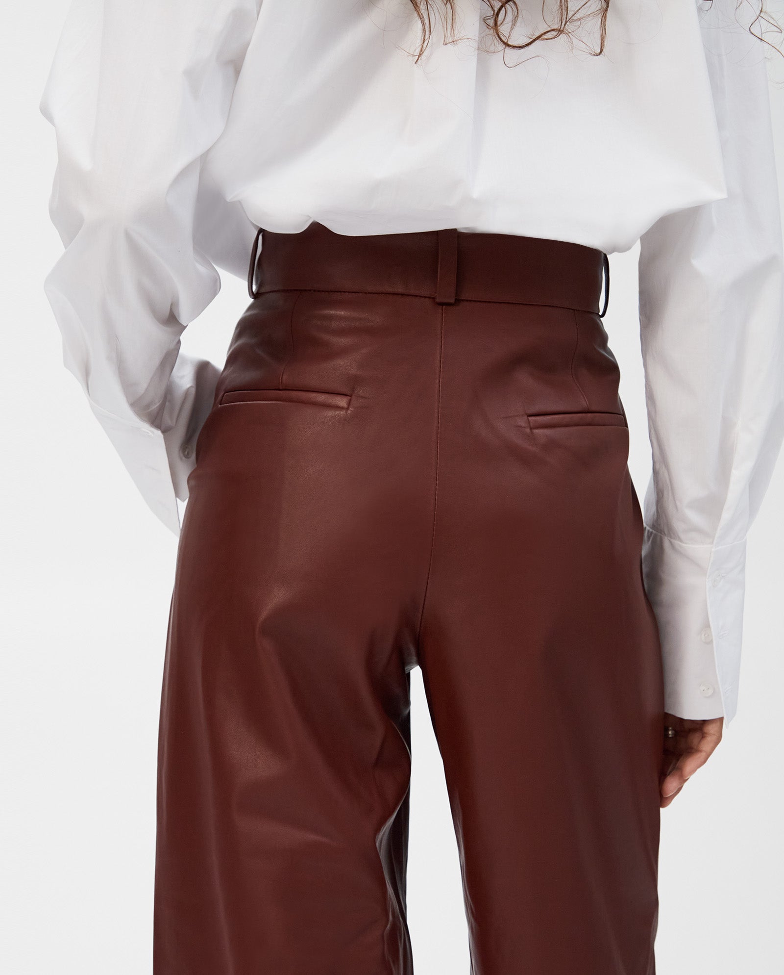 Model wearing the IVY OAK LORAINE Trousers—classic-cut, high-waisted leather pants—paired with a white shirt and shown from the back for a modern look.