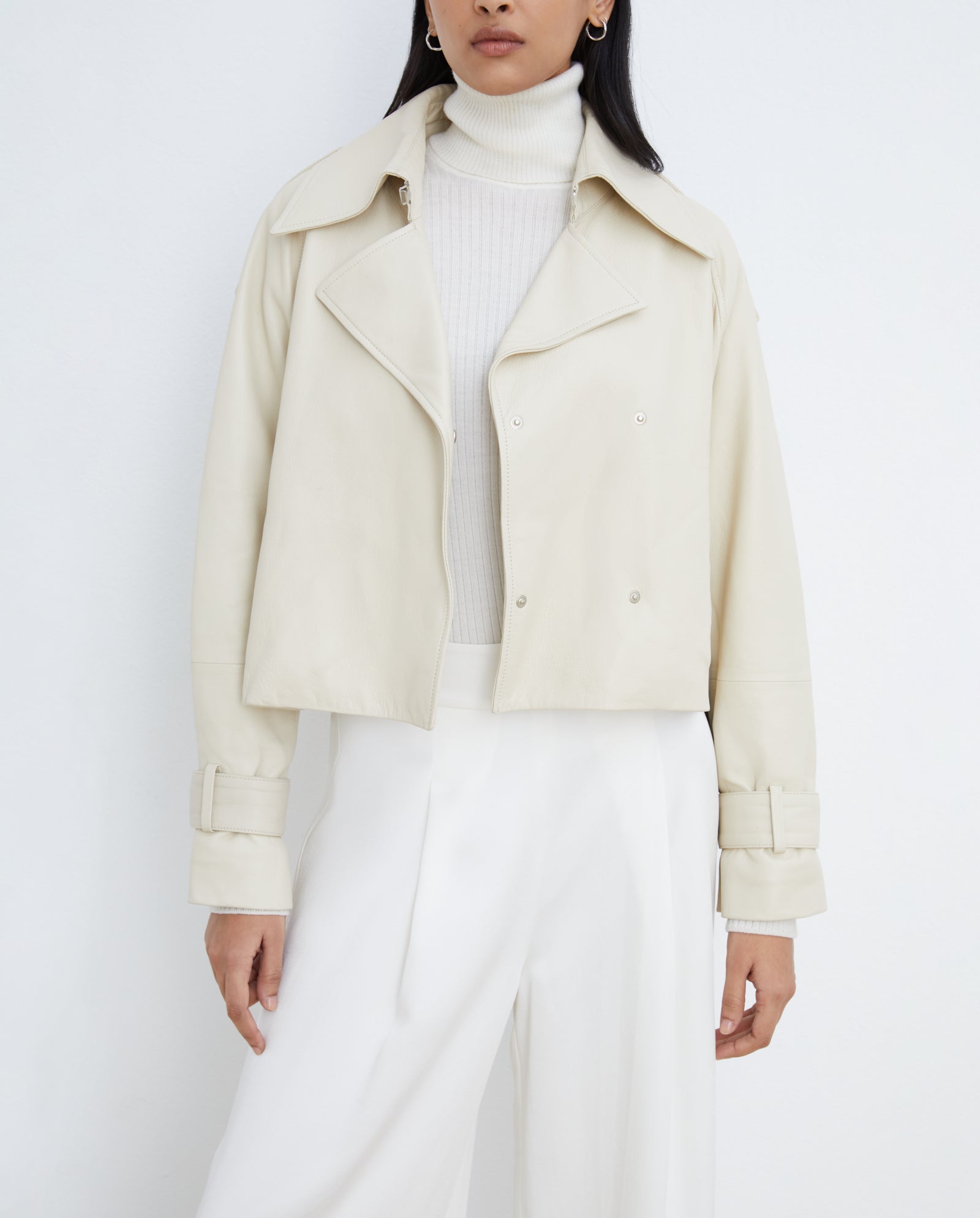 A woman wears the IVY OAK LILITH ANN off-white jacket with a large collar, paired with a turtleneck sweater and white pants, set against a plain background.