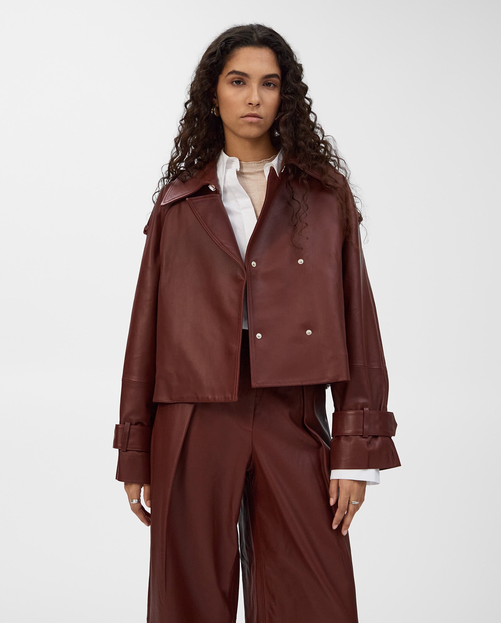 A person stands against a plain background wearing an IVY OAK LILITH ANN jacket with a large collar and pants over a white shirt.