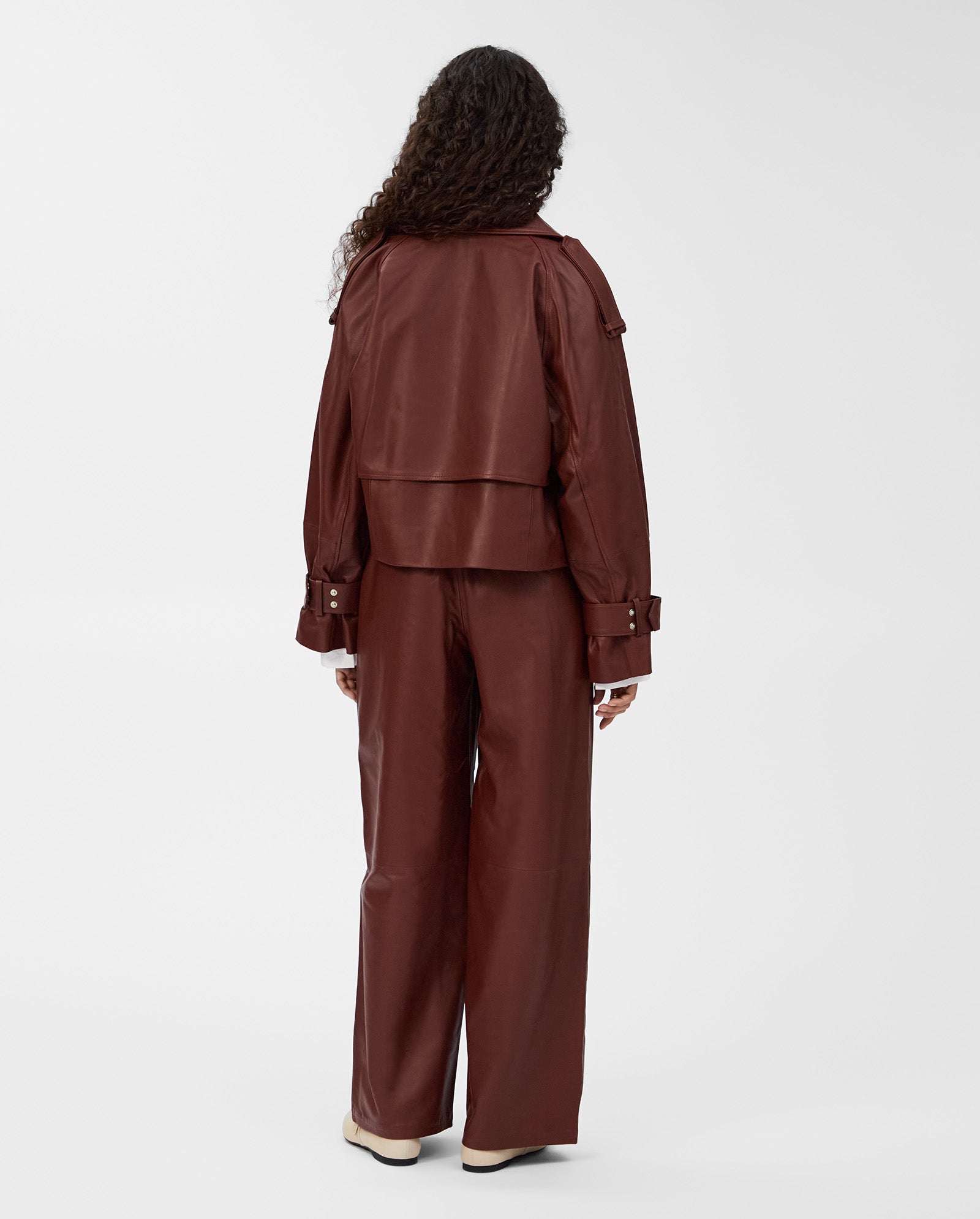 Person standing with back to camera, wearing a brown IVY OAK LILITH ANN Jacket with a large collar and matching wide-leg pants.