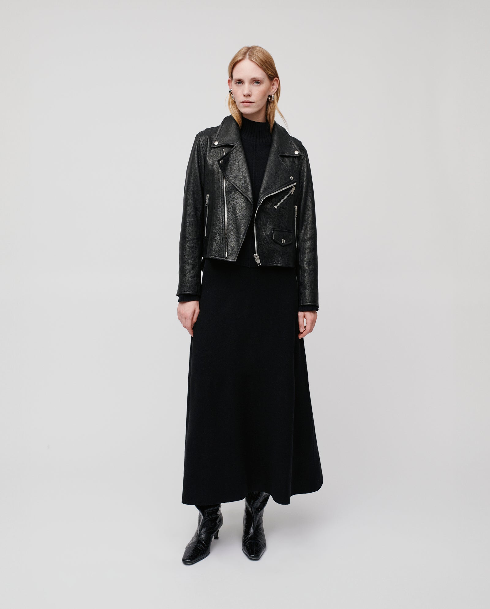 A woman wears the IVY OAK LENNY SUE Jacket, crafted from chrome-free tanned leather, styled with a black turtleneck and long skirt, standing against a plain background.