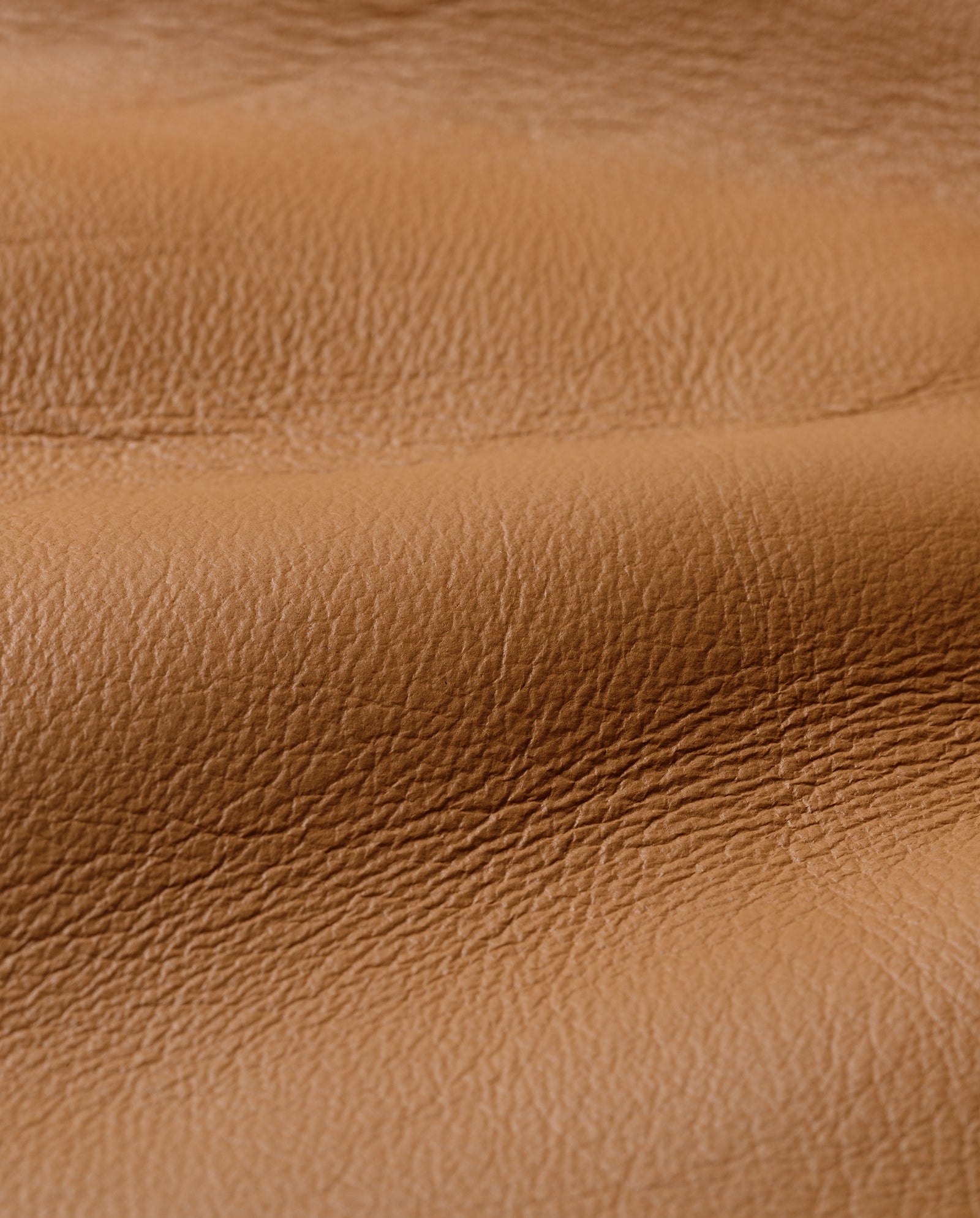 Close-up of tan textured leather with natural creases and grain, reminiscent of a boxy shearling jacket like the LOTTE Jacket by IVY OAK.