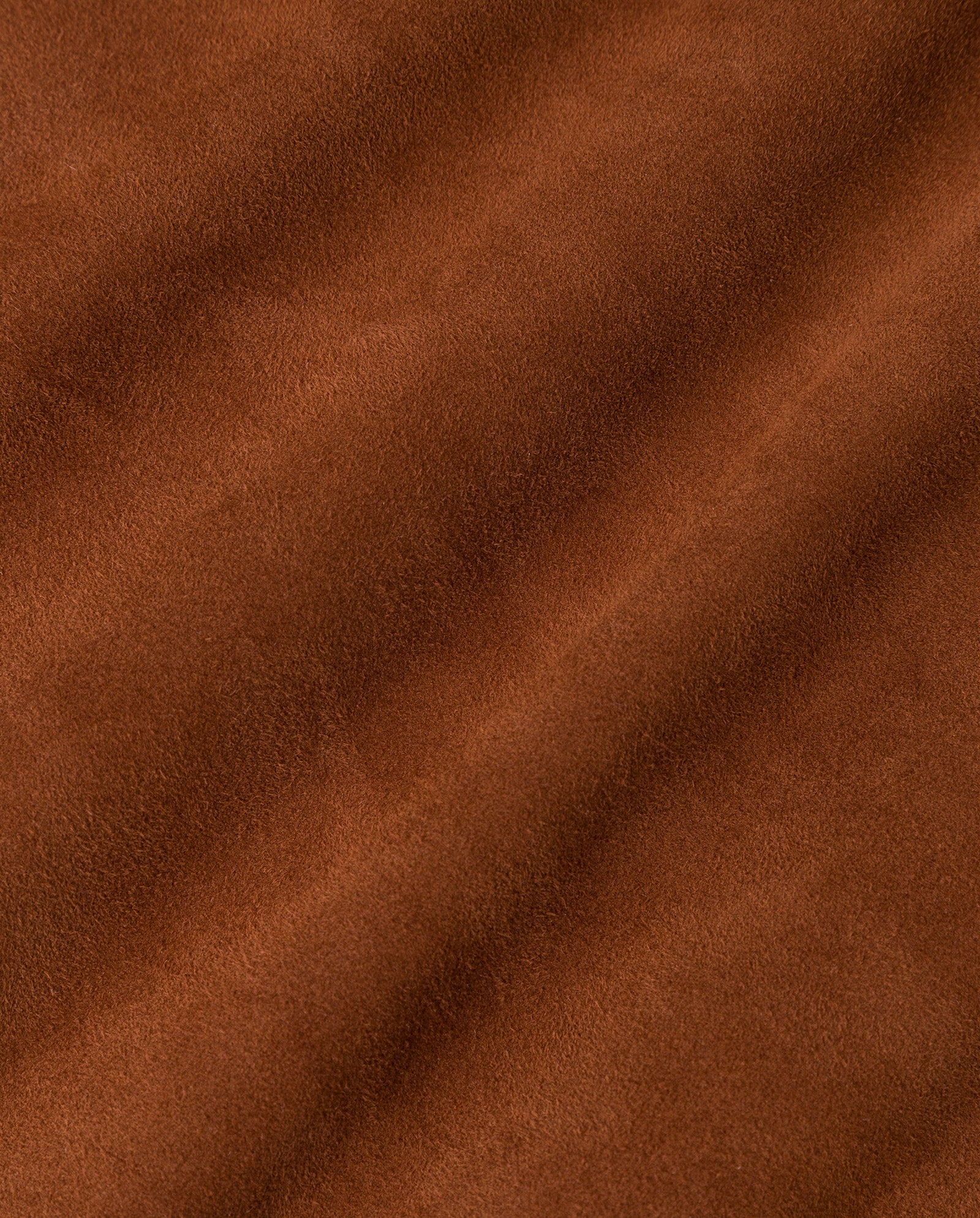 Close-up of brown suede fabric with soft texture and gentle, wavy folds, featured in the LENA Jacket by IVY OAK—ideal for a cropped boxy silhouette or suede bomber style.