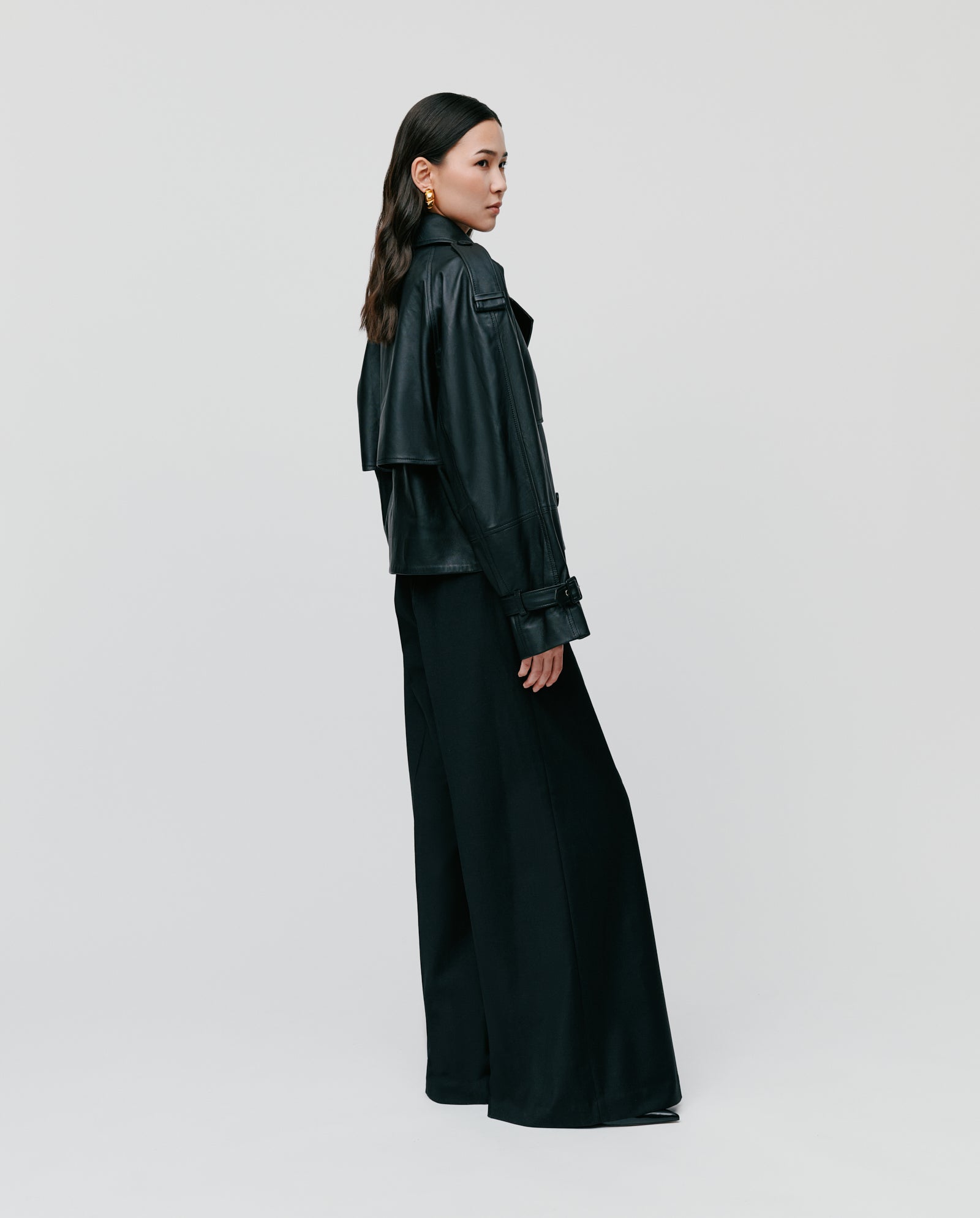 A woman stands sideways against a plain light background, wearing the IVY OAK LUNA Jacket styled with wide-leg pants.