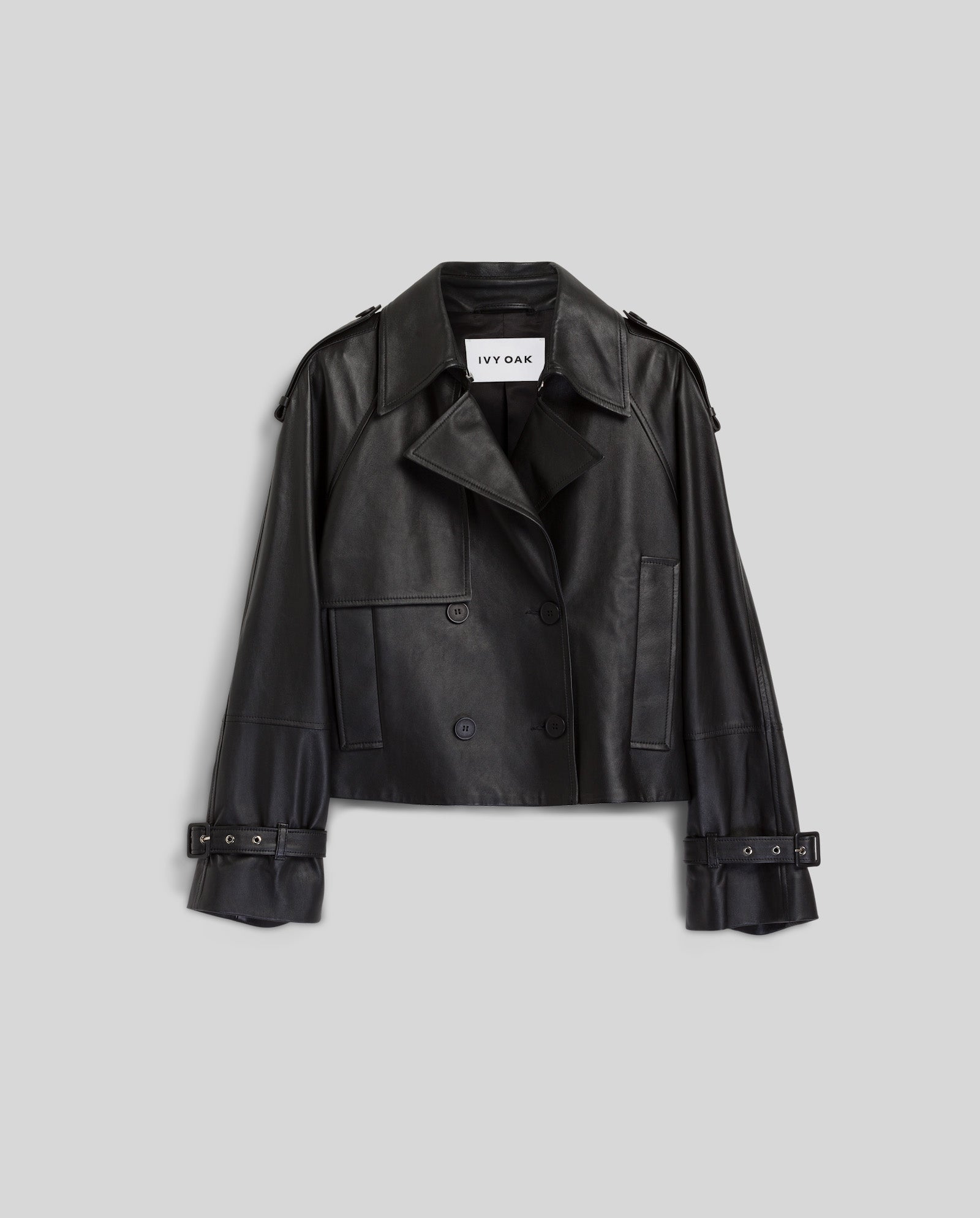 The IVY OAK LUNA Jacket is a black cropped oversized leather jacket featuring lapels, double-breasted button closure, and belted cuffs, shown against a gray background.