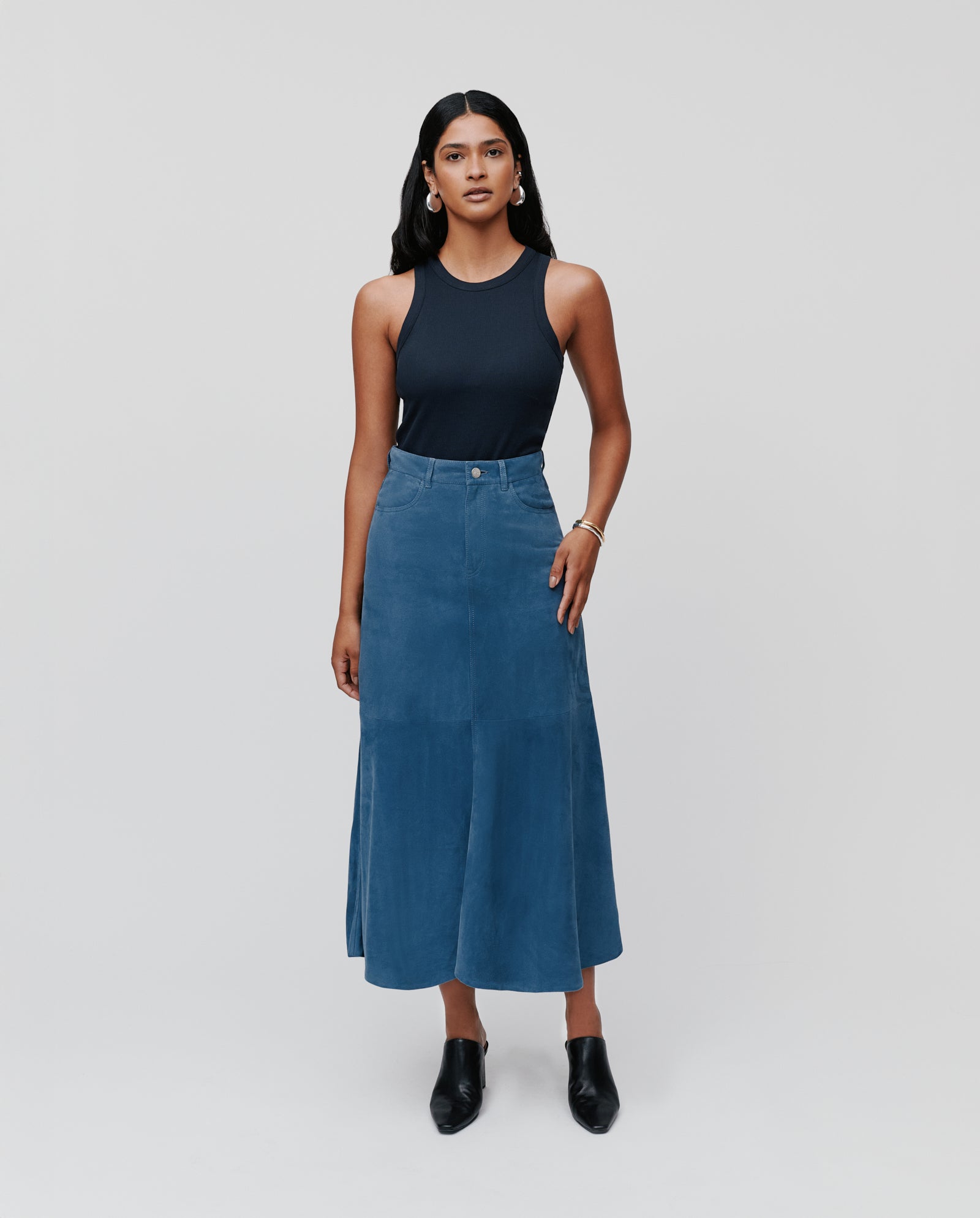 Woman wearing a navy sleeveless top and high-waist blue LACY Skirt by IVY OAK, standing against a plain light background.