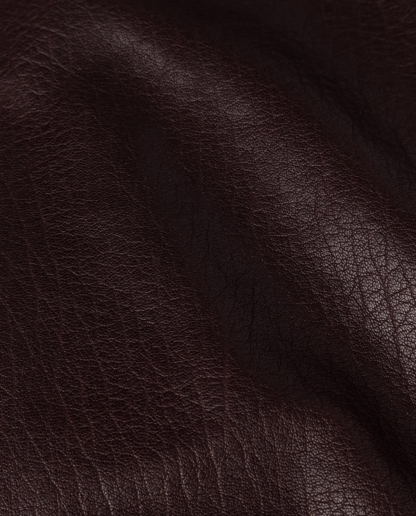 Close-up of dark brown, textured leather—crafted from premium hide—with visible grain and subtle creases, perfect for the oversized LARA Jacket by IVY OAK.