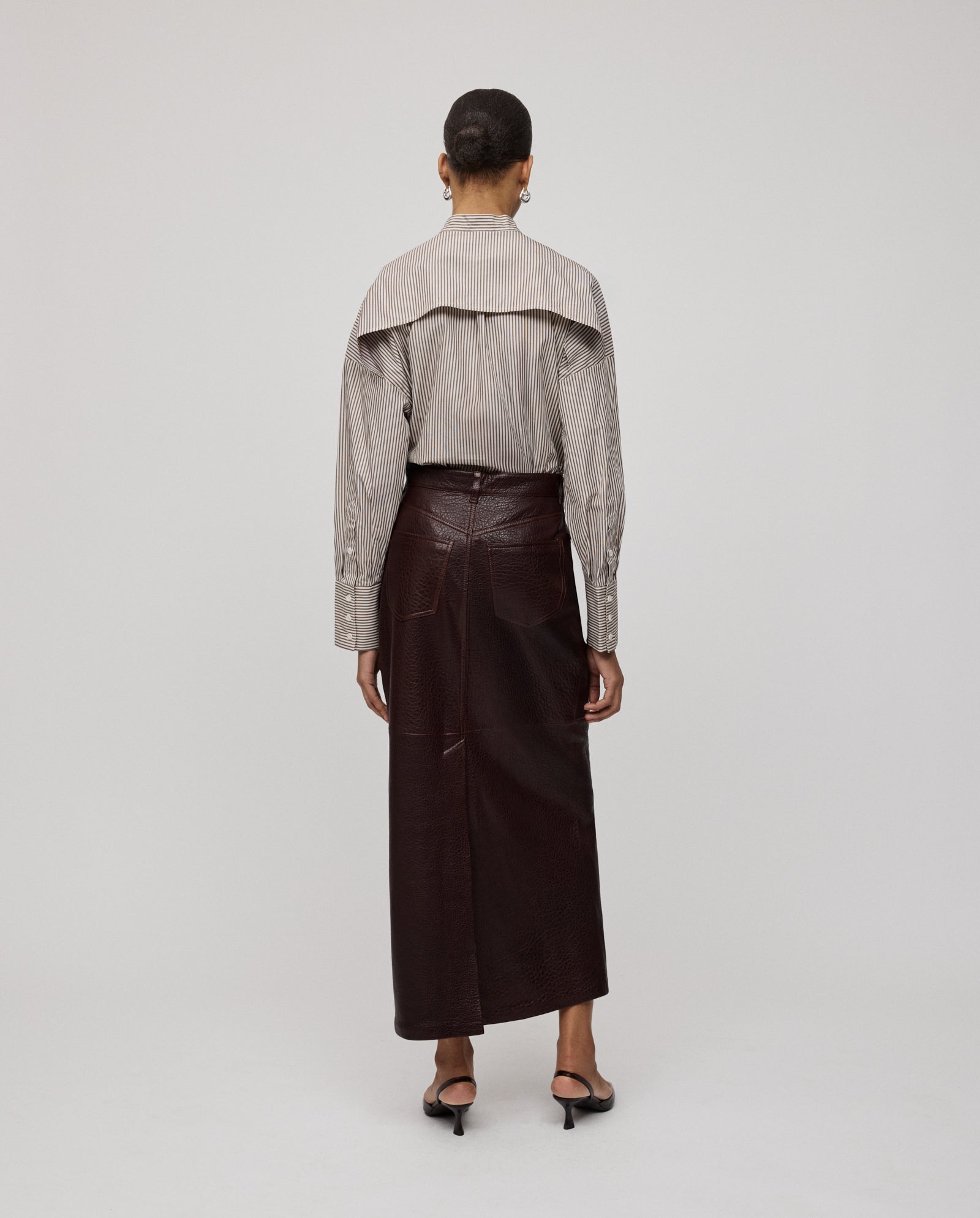 A person stands facing away against a plain background, wearing the IVY OAK LISANNE Skirt, an ankle-length A-line skirt paired with a striped blouse.