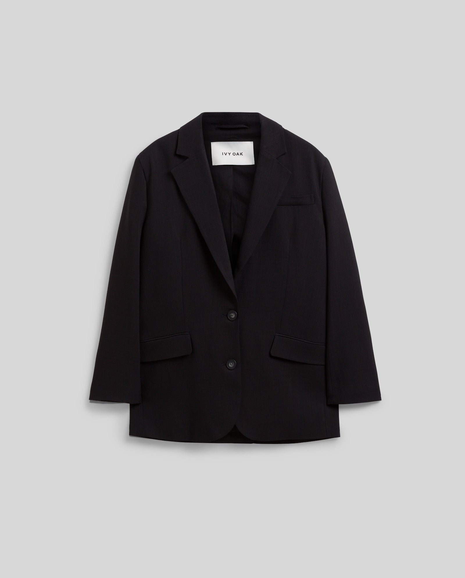 The IVY OAK JUNA Blazer is a black, single-breasted jacket featuring two buttons, notched lapels, and front pockets, shown on a gray background.