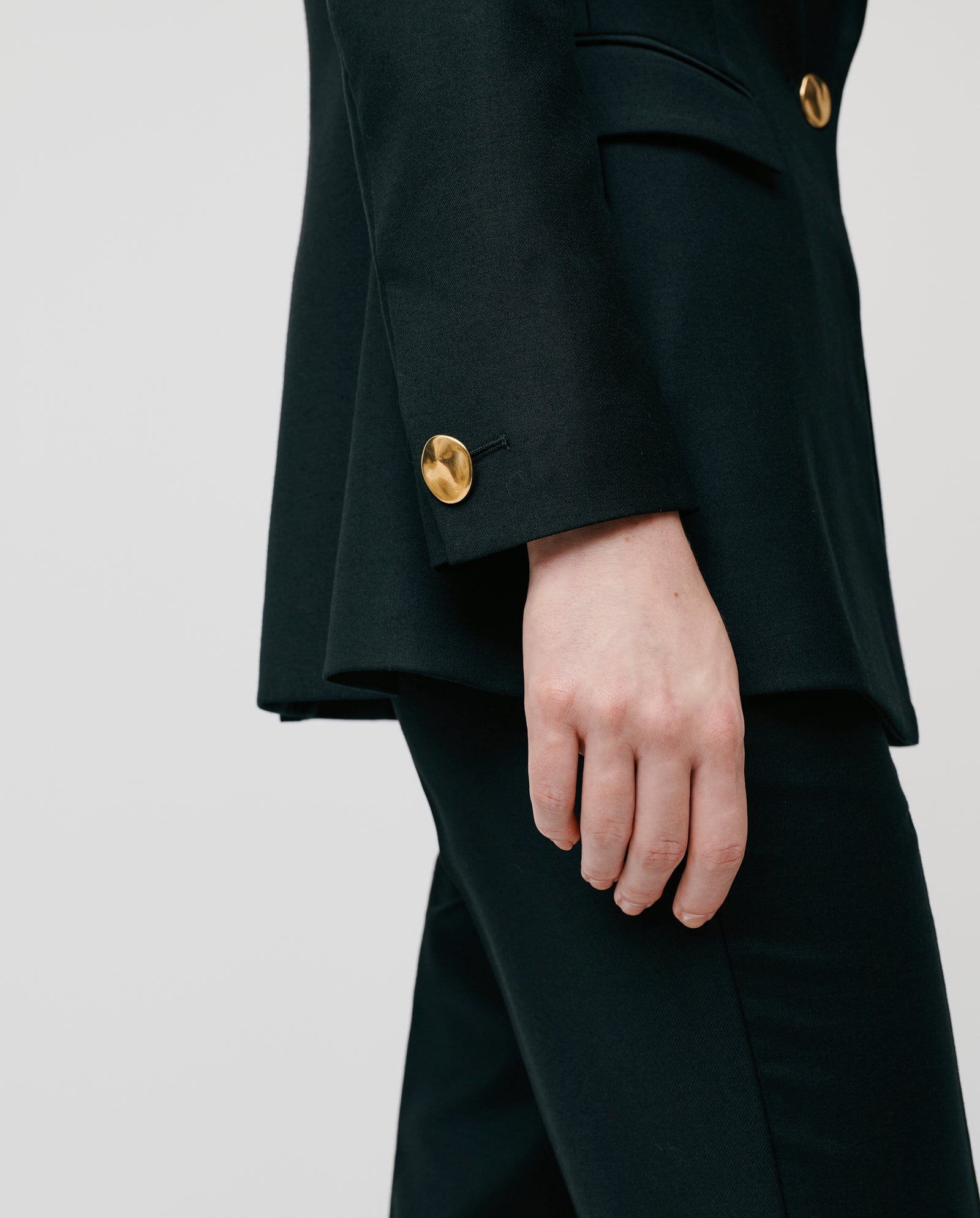 A person wears the IVY OAK JOLANKA Blazer with gold buttons and matching trousers, shown waist down with their hand relaxed at their side.