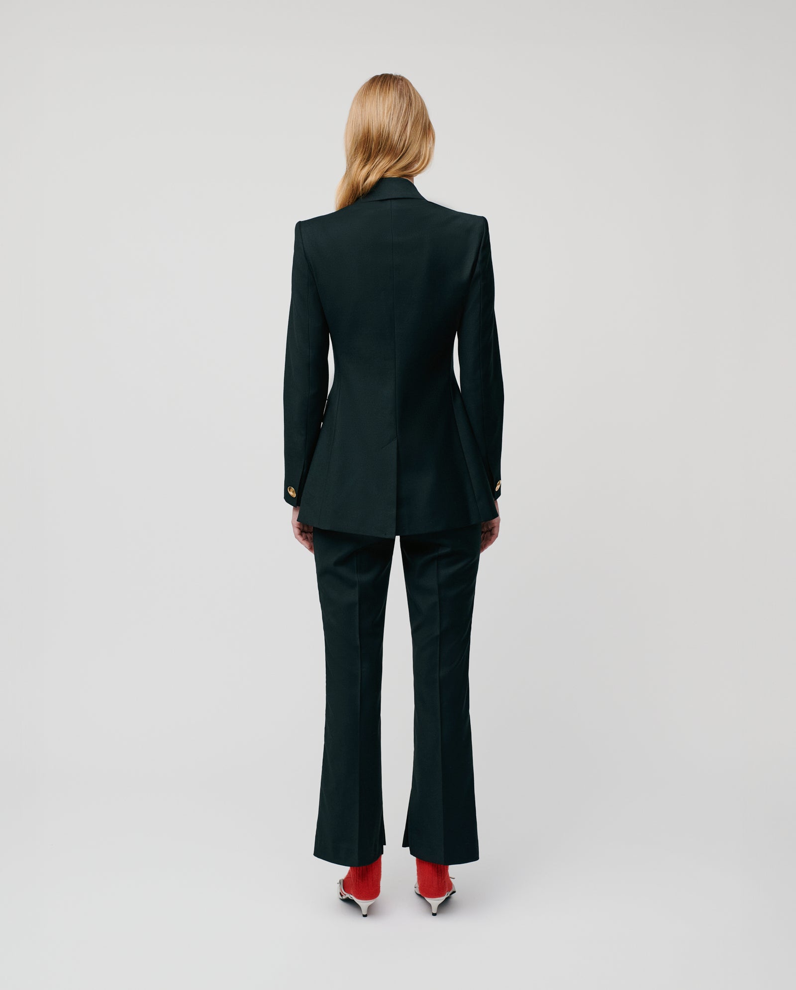 Model wearing the IVY OAK JOLANKA Blazer with gold-tone buttons, paired with red shoes, stands against a plain background facing away from the camera.