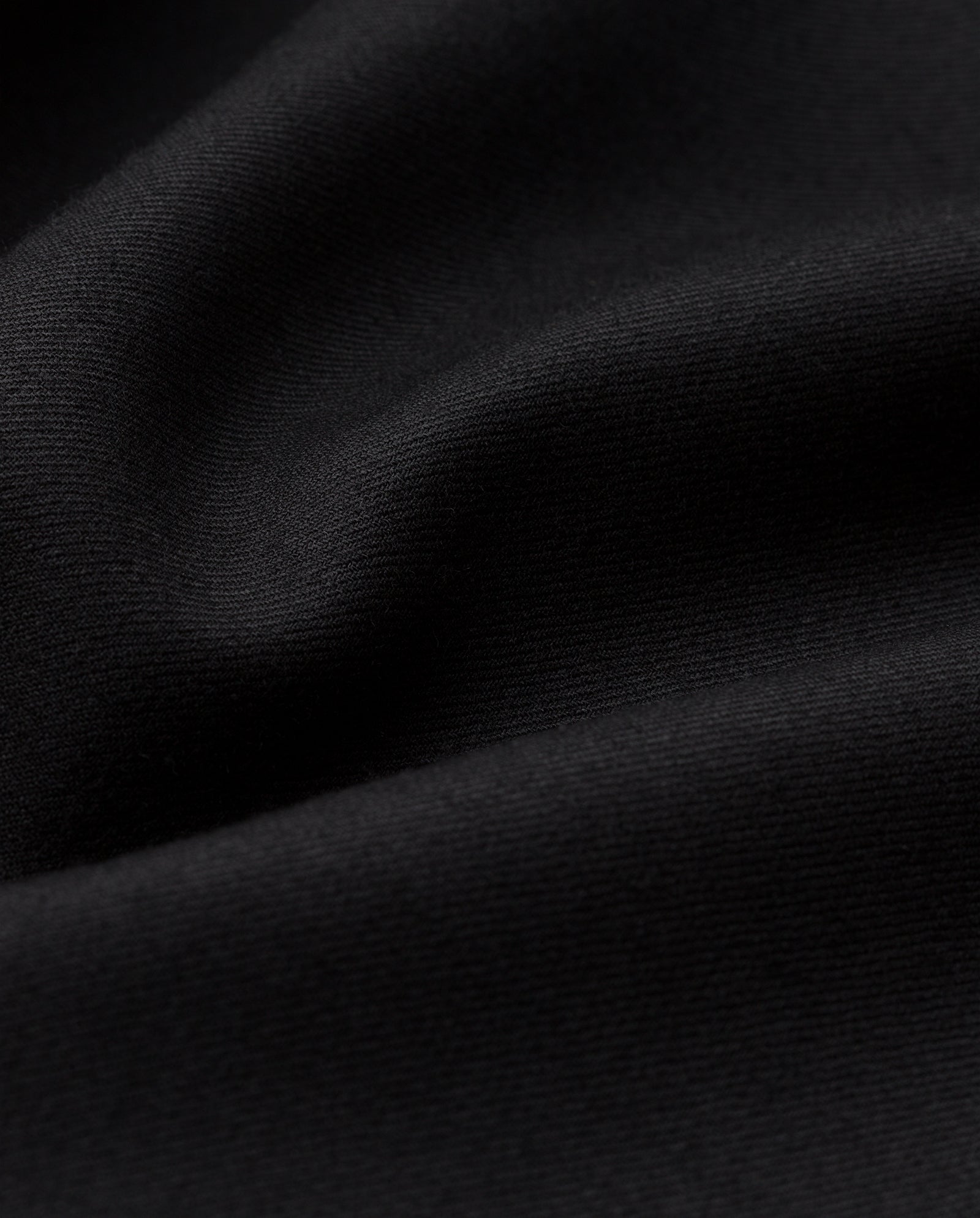 Close-up of smooth black fabric with soft folds highlights the elegance of the IVY OAK JOLANKA Blazer, featuring refined golden button details.