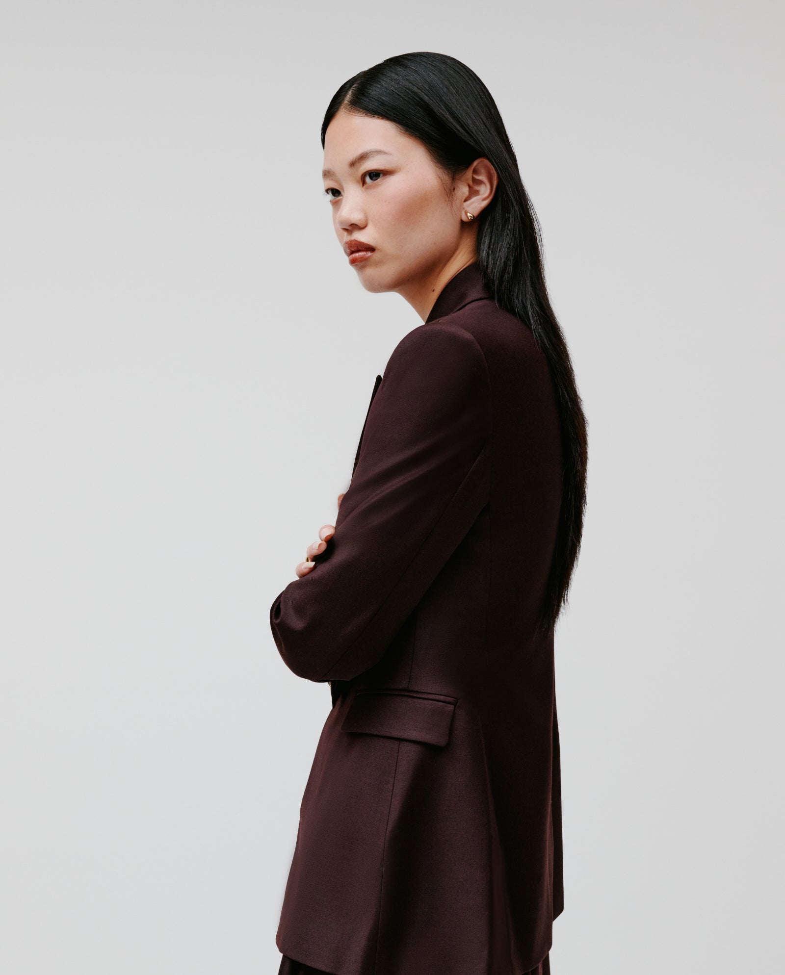 Model with long black hair, wearing the IVY OAK JOLANKA Blazer, stands sideways with arms crossed against a plain background.