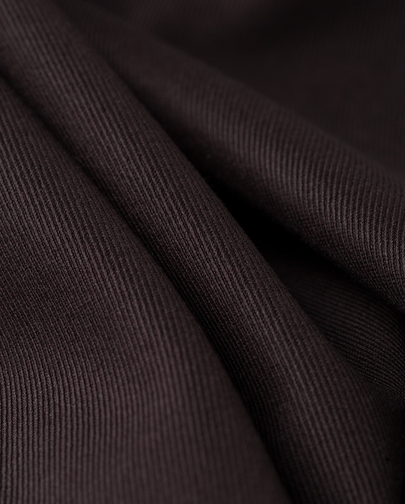 Close-up of soft, dark brown ribbed fabric with gentle folds and texture—perfect for creating the JACQUELINE Blazer by IVY OAK, known for its statement boxy fit.