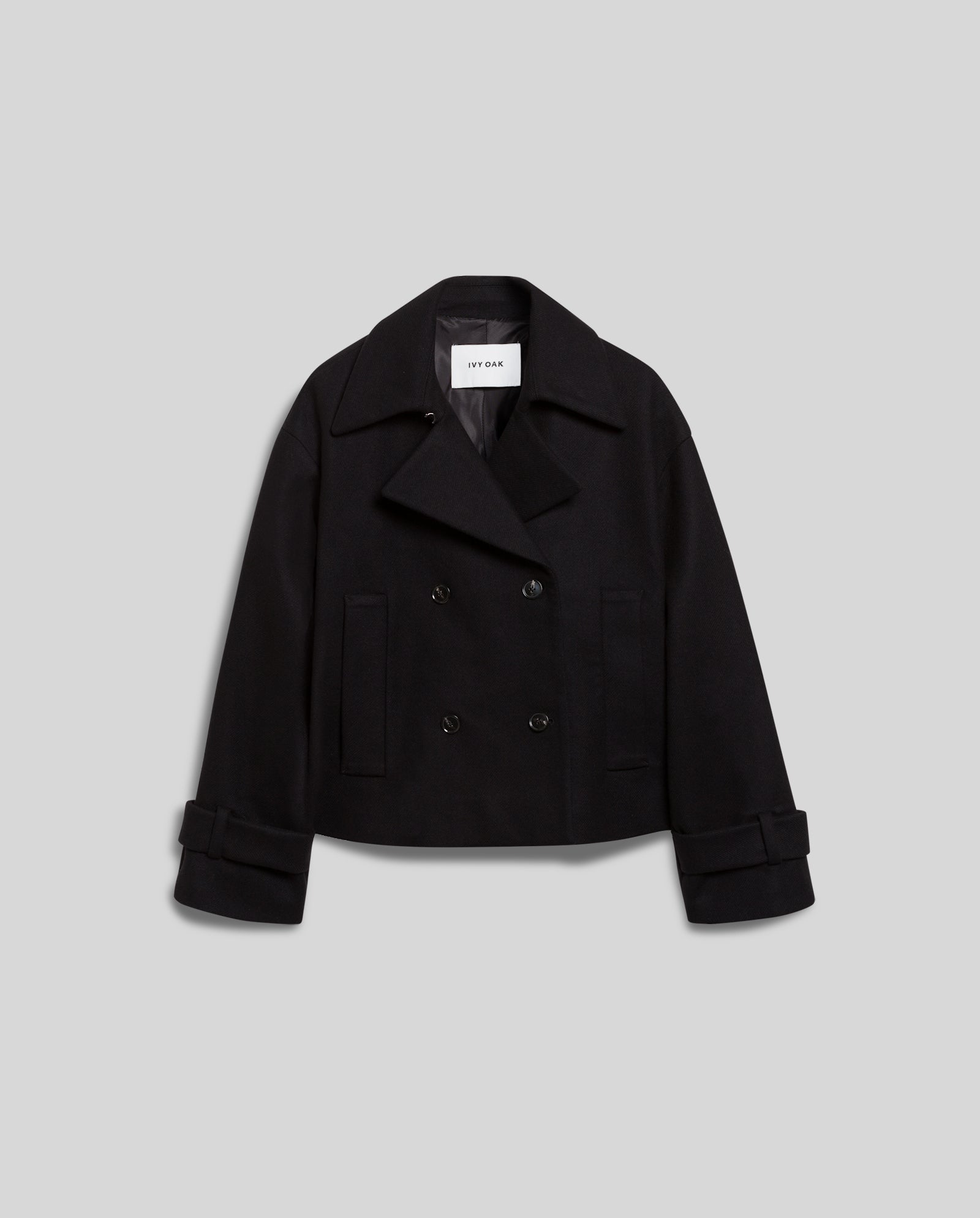 The JANET Jacket by IVY OAK is a black cropped double-breasted peacoat crafted from RWS-certified wool and cashmere blend, featuring wide lapels and cuffed sleeves, shown on a light gray background.
