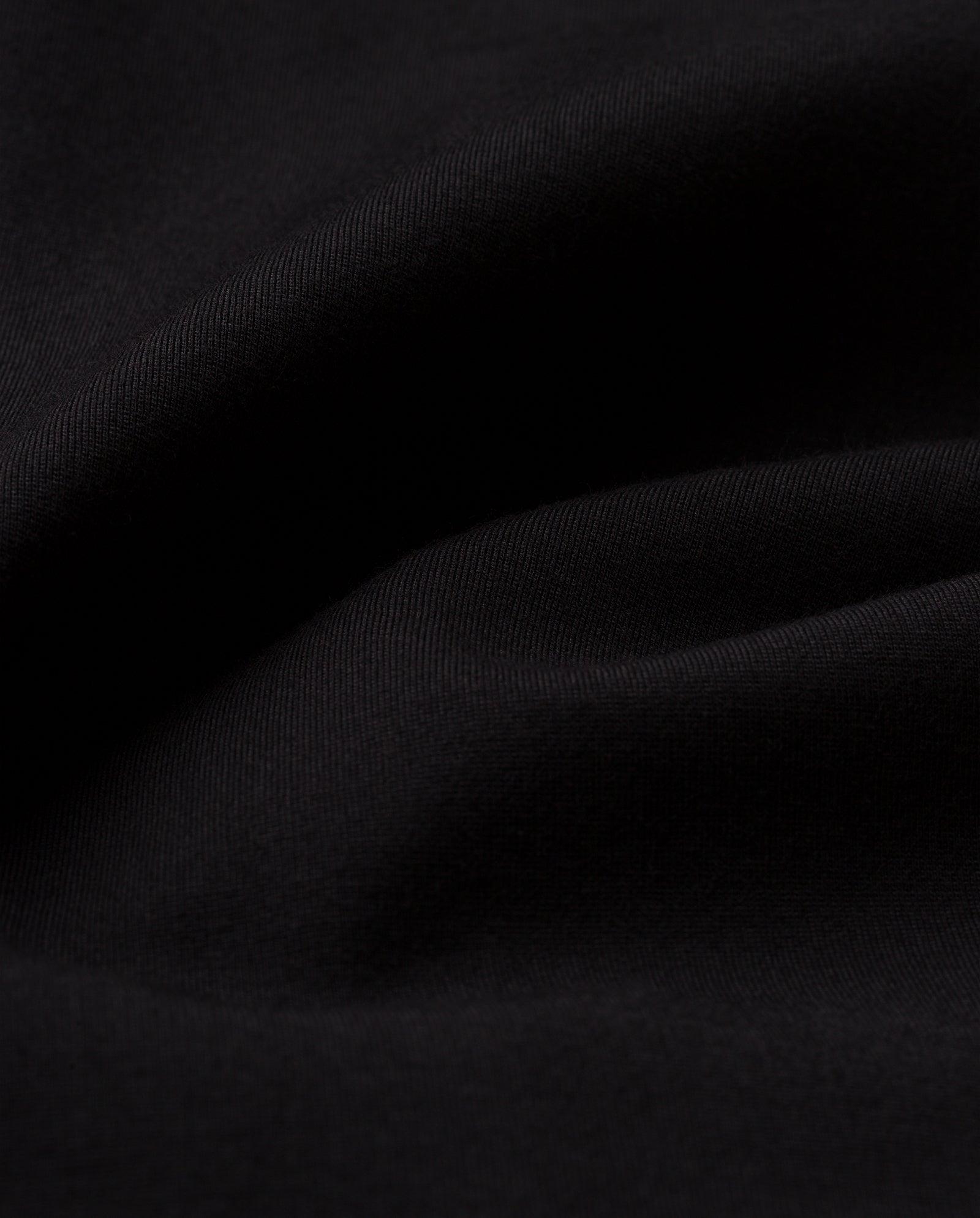 Close-up of black, slightly wrinkled fabric with visible texture and soft folds, evoking the elegant silhouette and refined details of the IVY OAK JOLANKA KIM Blazer.