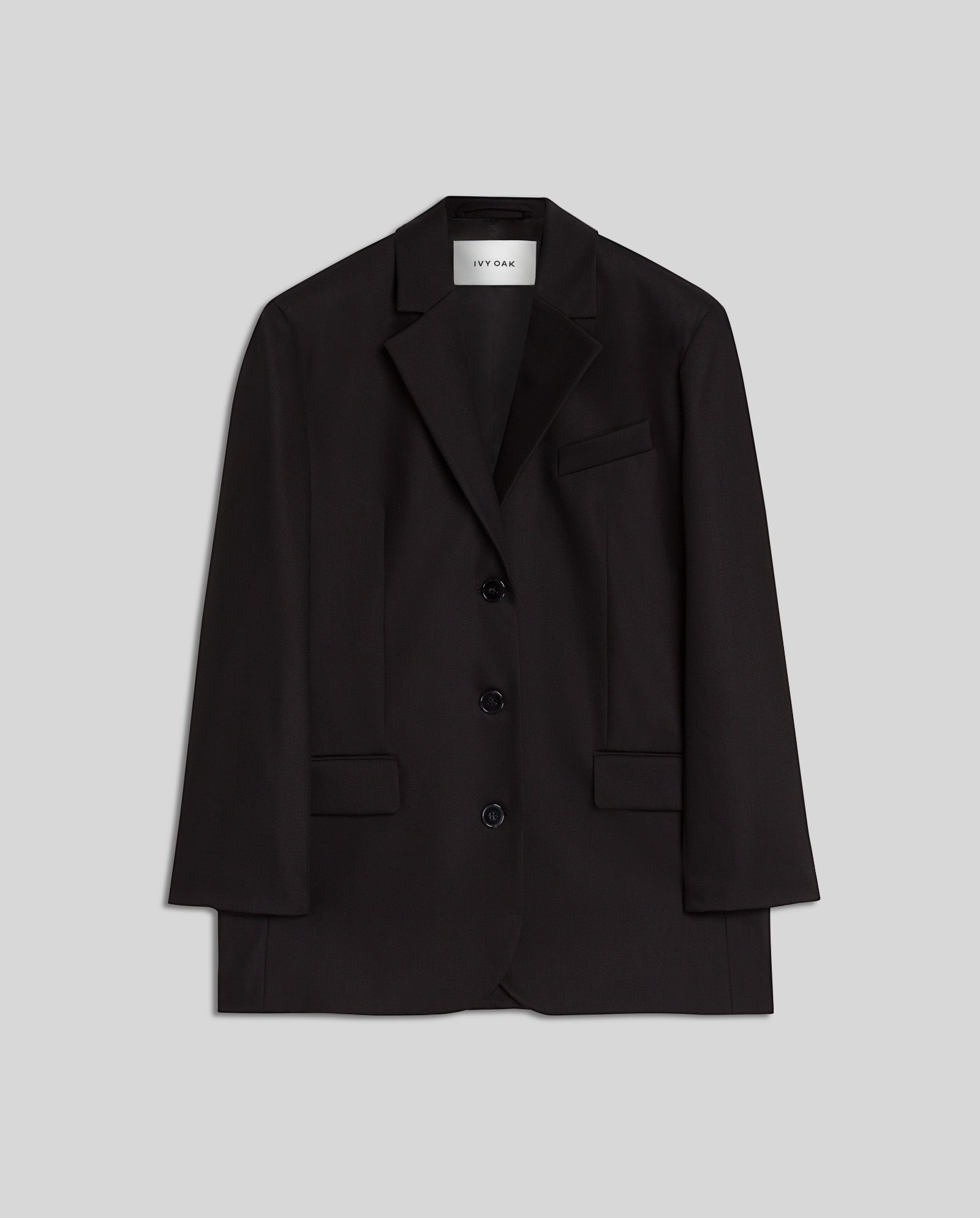 The IVY OAK JACQUELINE Blazer is a black, single-breasted piece with three buttons, front pockets, and a boxy fit, shown against a light gray background.