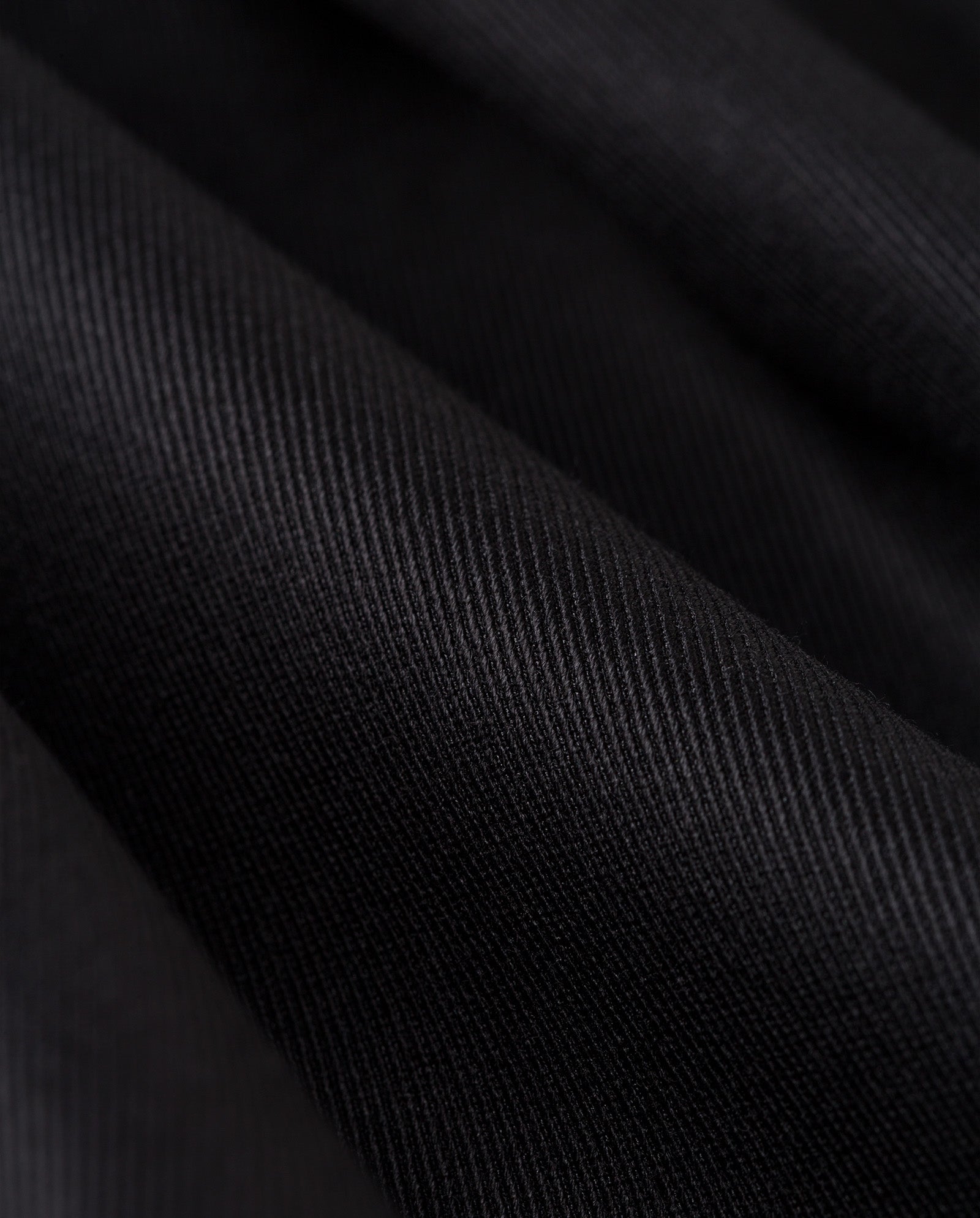 Close-up of black fabric with visible diagonal weave and gentle folds, perfect for creating the IVY OAK JACQUELINE Blazer with a stylish oversized fit.