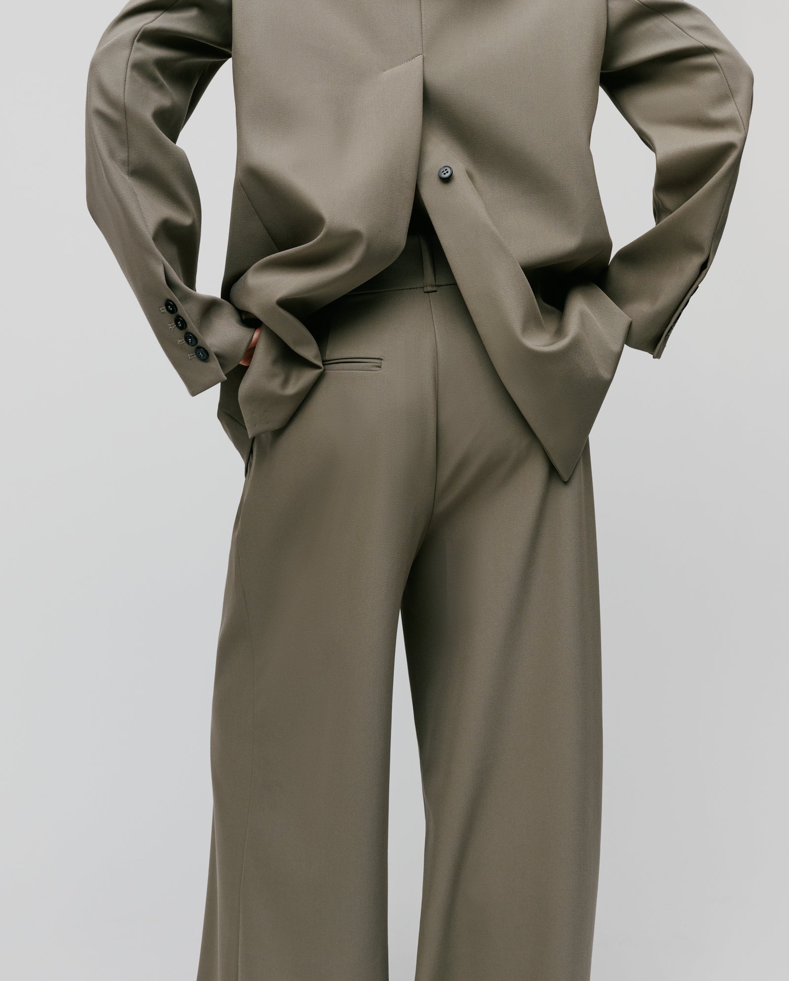 Person wearing the IVY OAK JACQUELINE Blazer in an oversized, boxy fit taupe style, photographed from behind with hands on hips against a plain background.