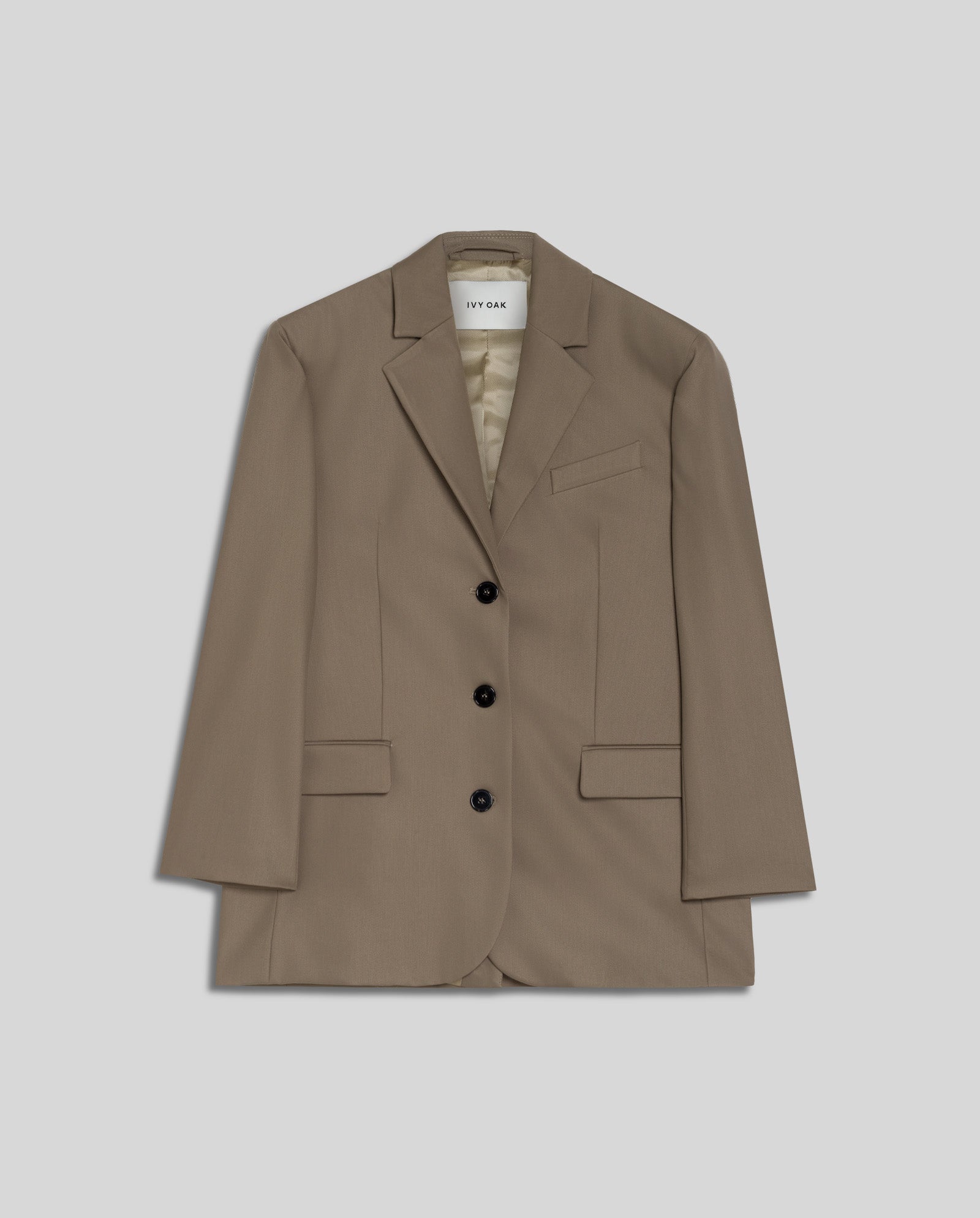 The IVY OAK JACQUELINE Blazer is a light brown, single-breasted style with a boxy fit, three black buttons, and front pockets, shown against a plain gray background.