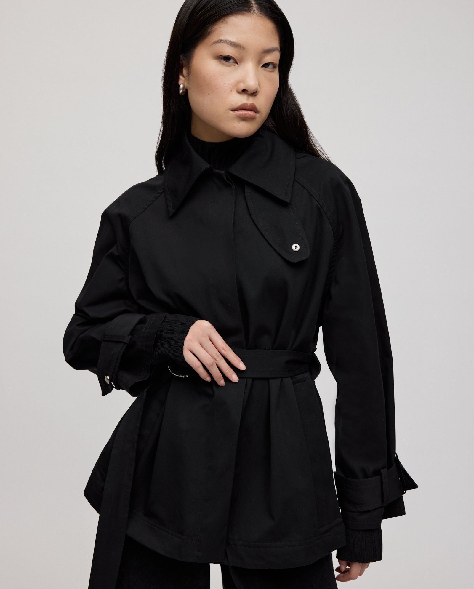 A woman with long dark hair models the IVY OAK JULES Jacket, featuring silver trim, over a black top against a plain background.