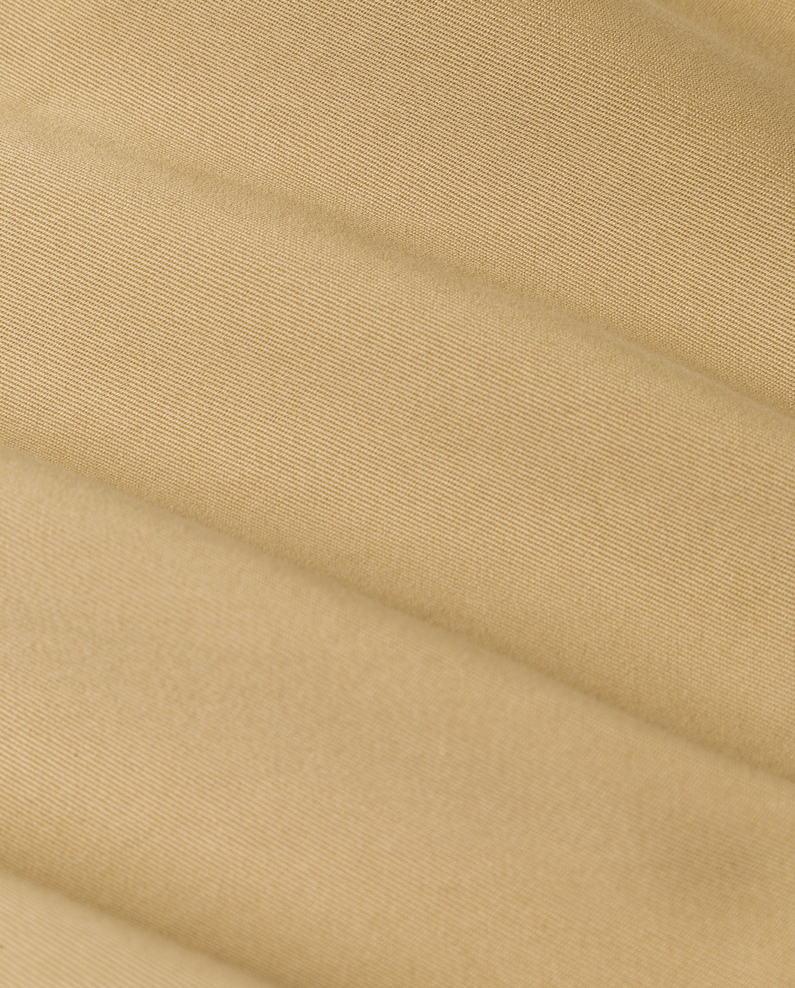 Close-up of the beige, textured fabric of the IVY OAK JESSICA Jacket, featuring diagonal, slightly raised lines and a smooth, soft appearance typical of classic trench coats.