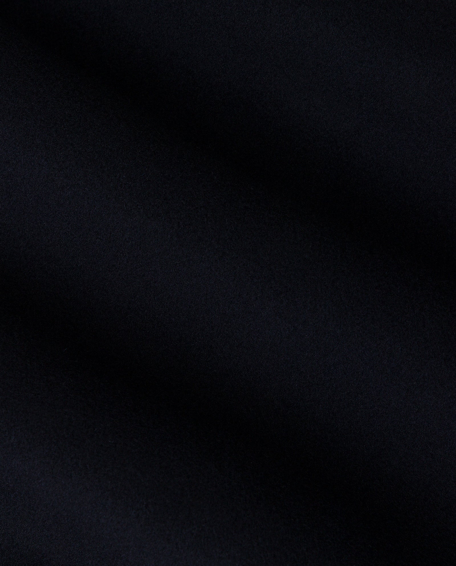 Close-up of smooth, dark black double-faced fabric with gentle waves and soft texture, perfect for the IVY OAK JAIA Wooljacket made from responsible wool.