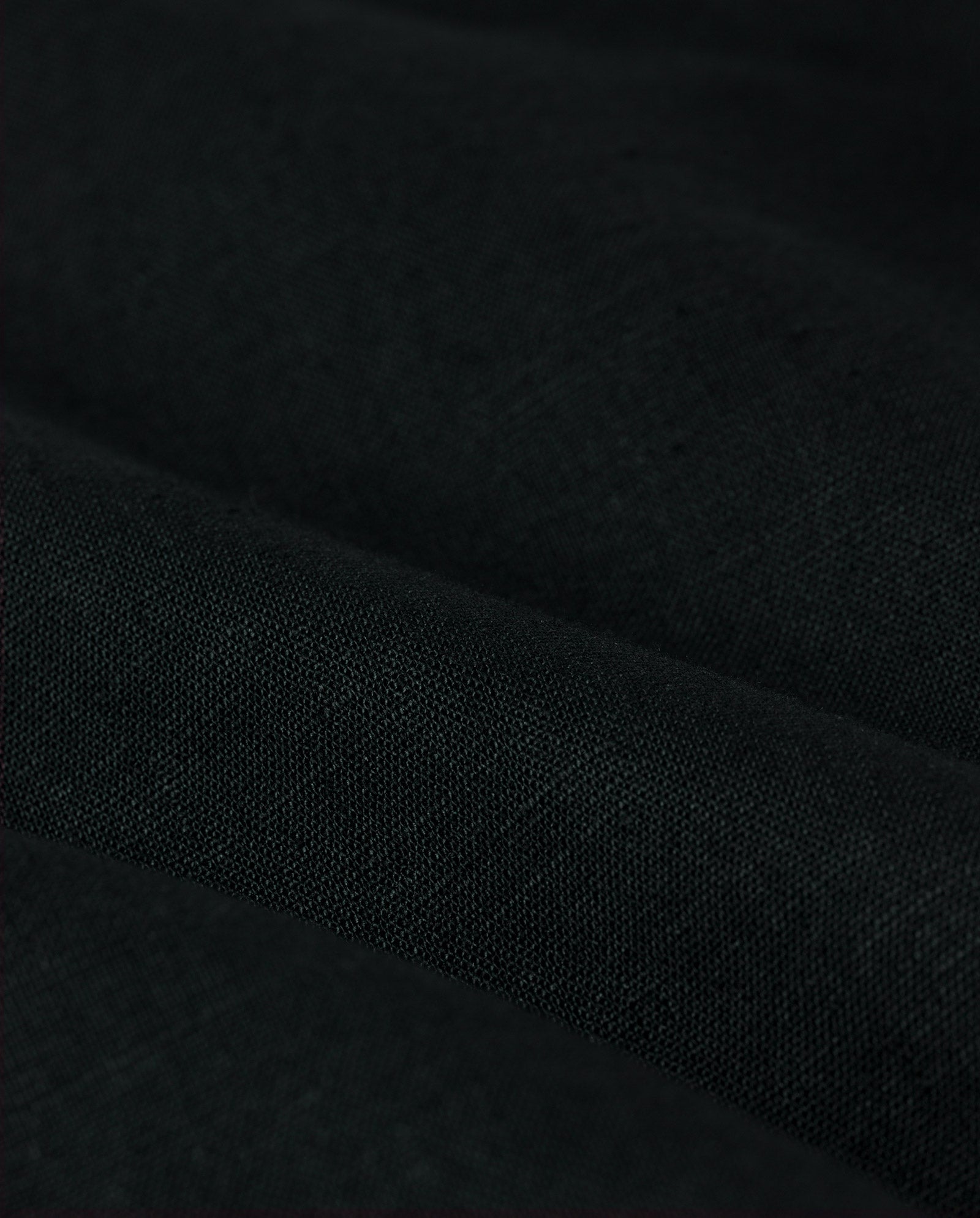 Close-up of black linen fabric with visible texture and folds, ideal for crafting the IVY OAK JASEMINA ROSE Blazer—perfect for menswear or a sophisticated look.