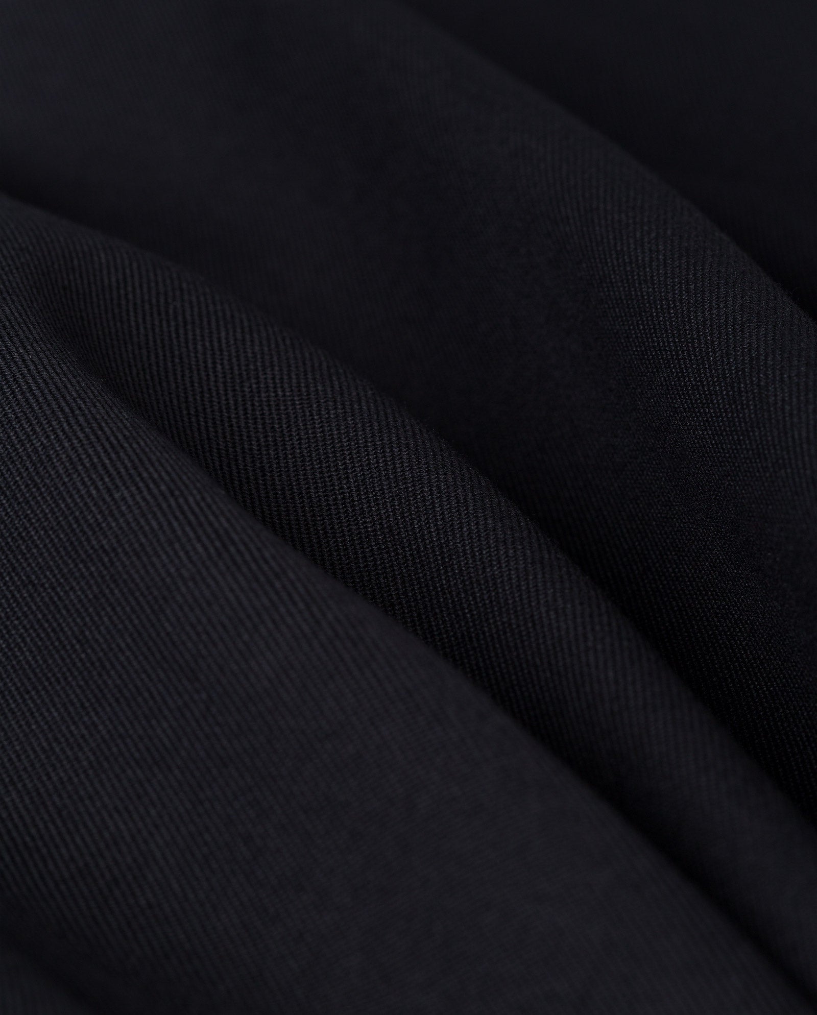 Close-up of black fabric with soft folds and diagonal weave—perfect for the IVY OAK JUNIPER ROSE Vest, crafted for sand glass silhouettes and unique cut-out details.