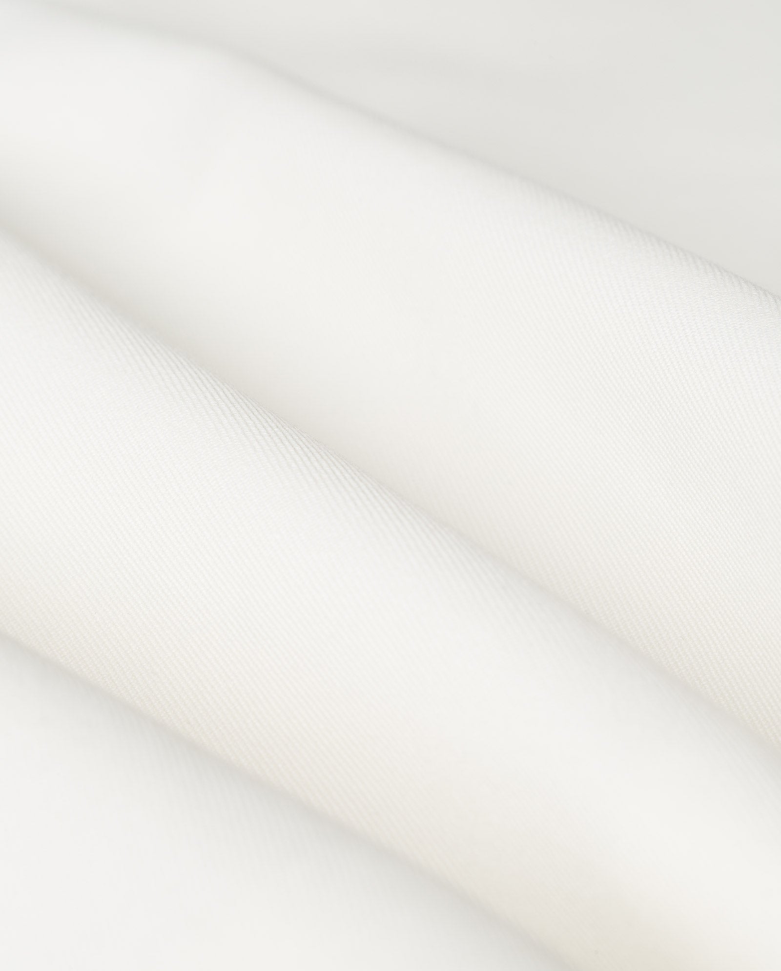 Close-up of the JUNIPER ROSE Vest by IVY OAK, showing smooth, folded white fabric with a soft texture, subtle diagonal lines, and a sleek button placket.