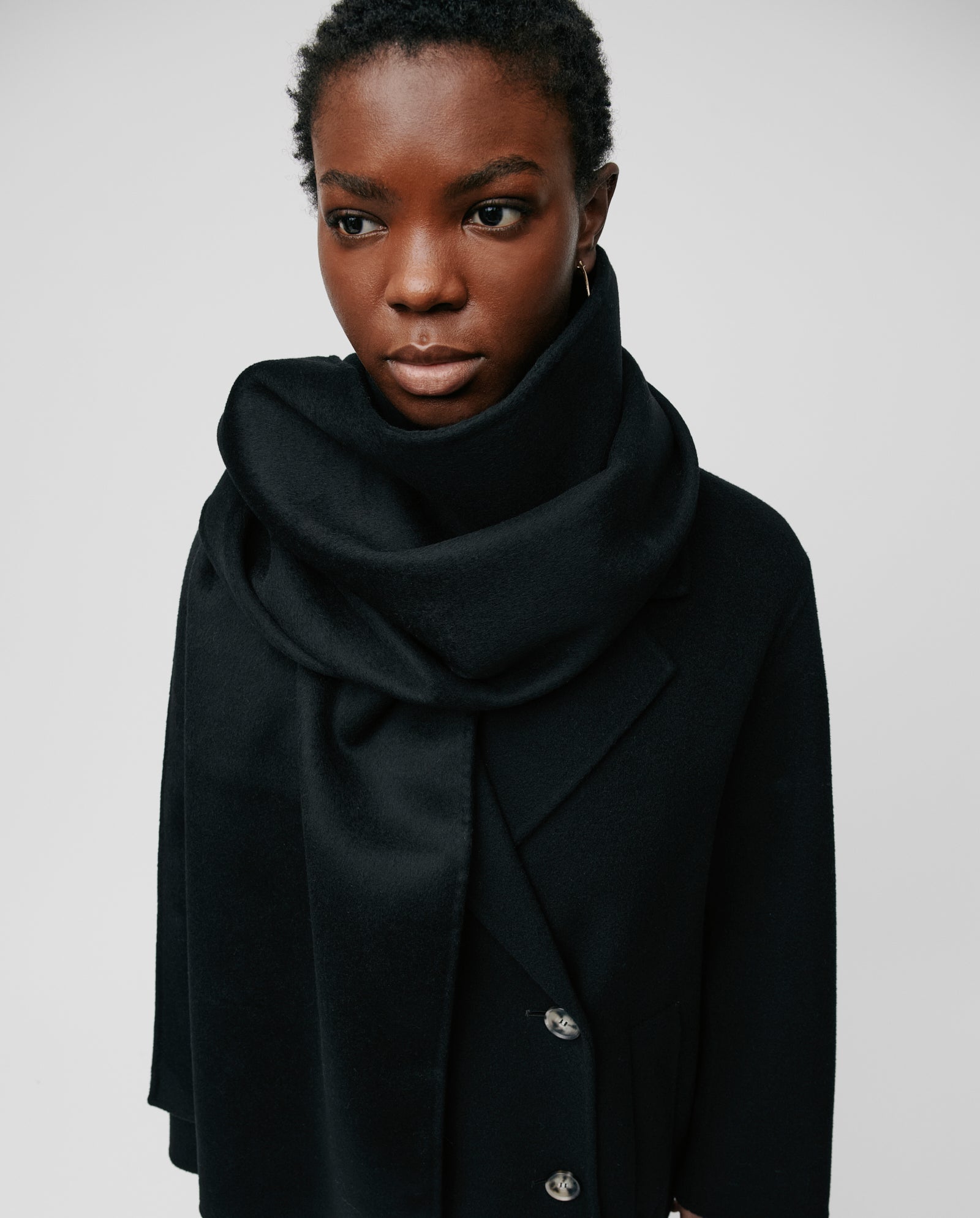 A person wearing a black coat and a large, cozy IVY OAK AMY Scarf wrapped around their neck, looking slightly to the side.