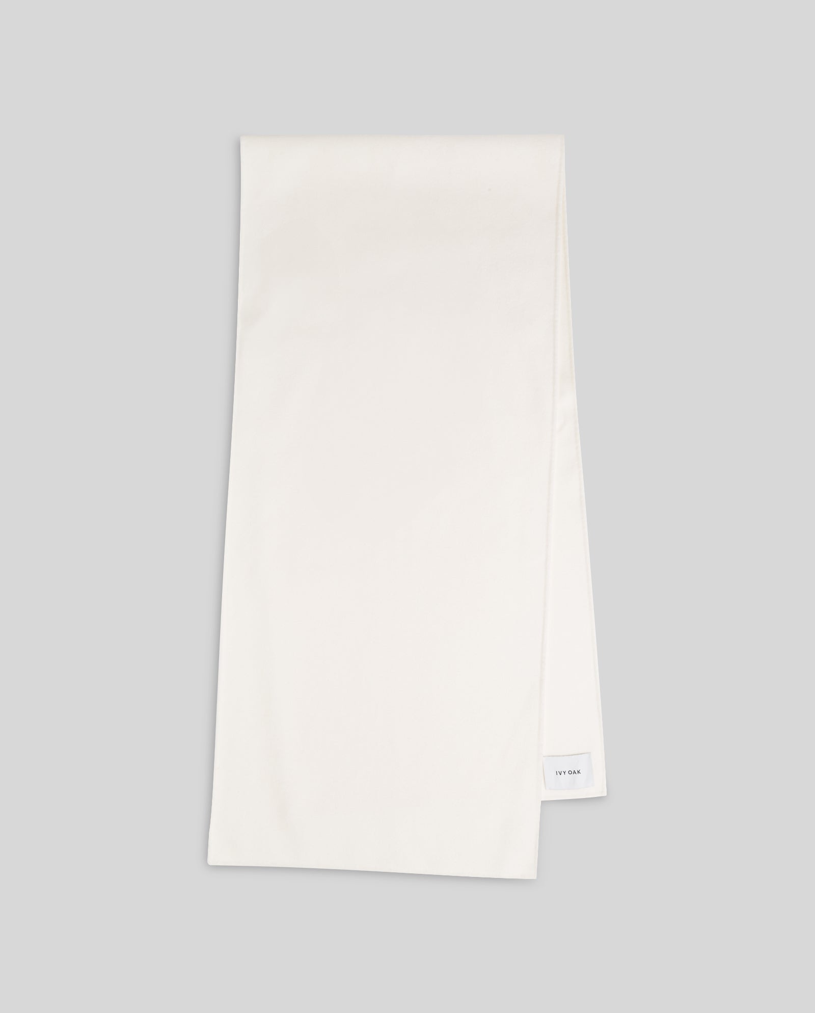 The IVY OAK AMY Wool Scarf, featuring a simple double face design and a subtle label, is neatly folded on a light gray background, highlighting its cozy white texture.