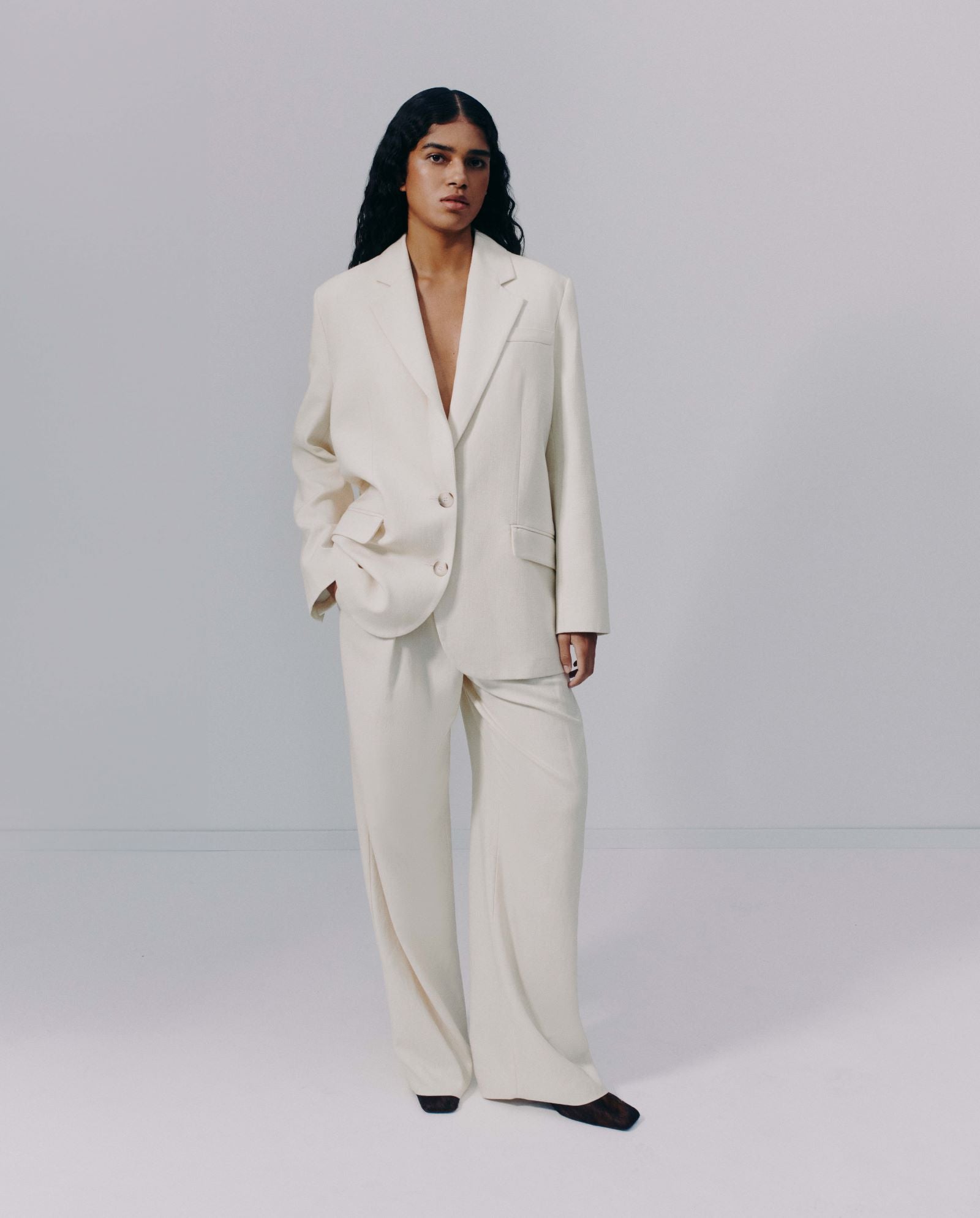 A person stands against a plain, light background wearing the IVY OAK JUNA Blazer in cream, featuring an oversized single-breasted design.