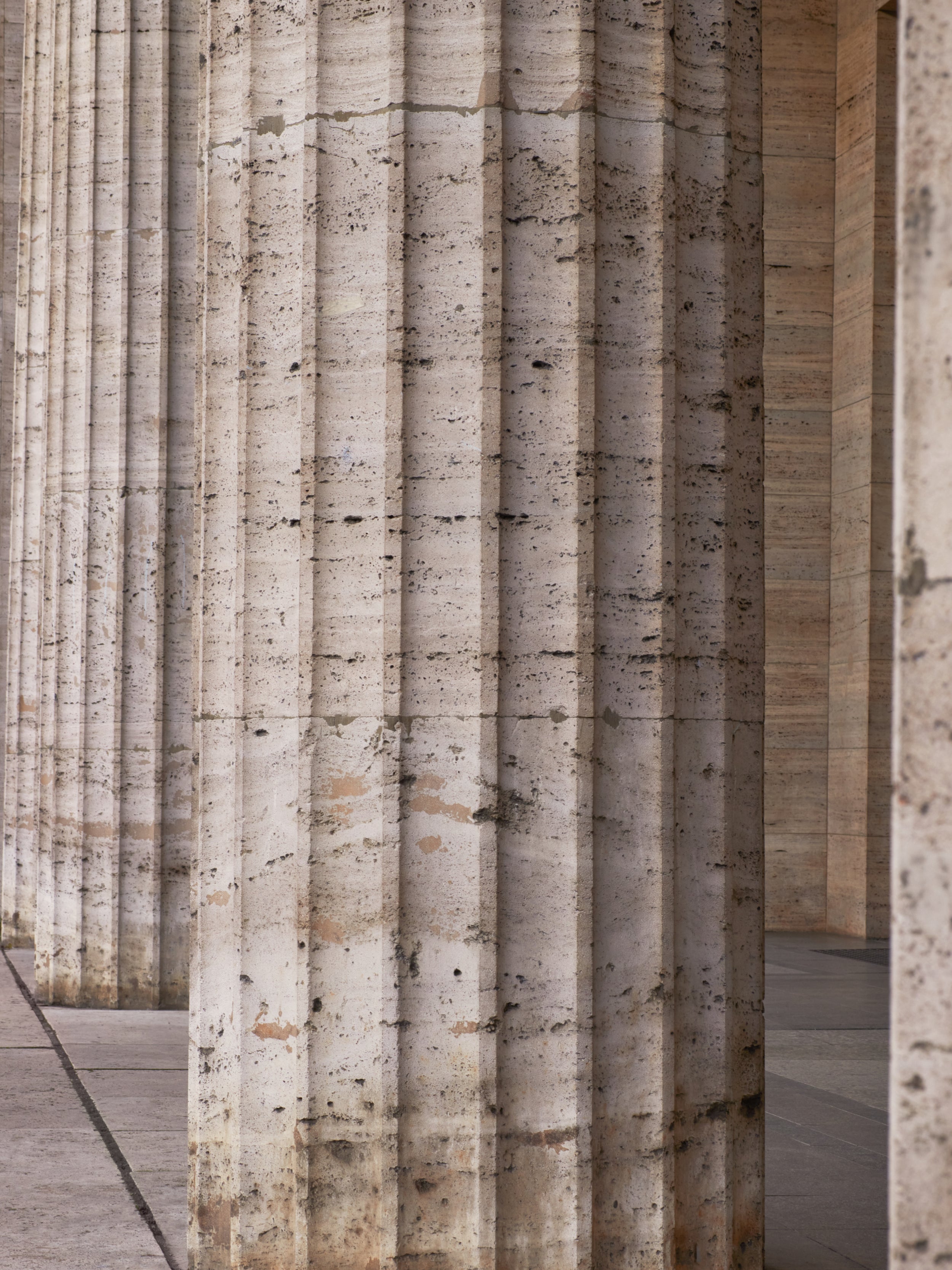Close-up view of large stone columns with vertical grooves and a textured surface.