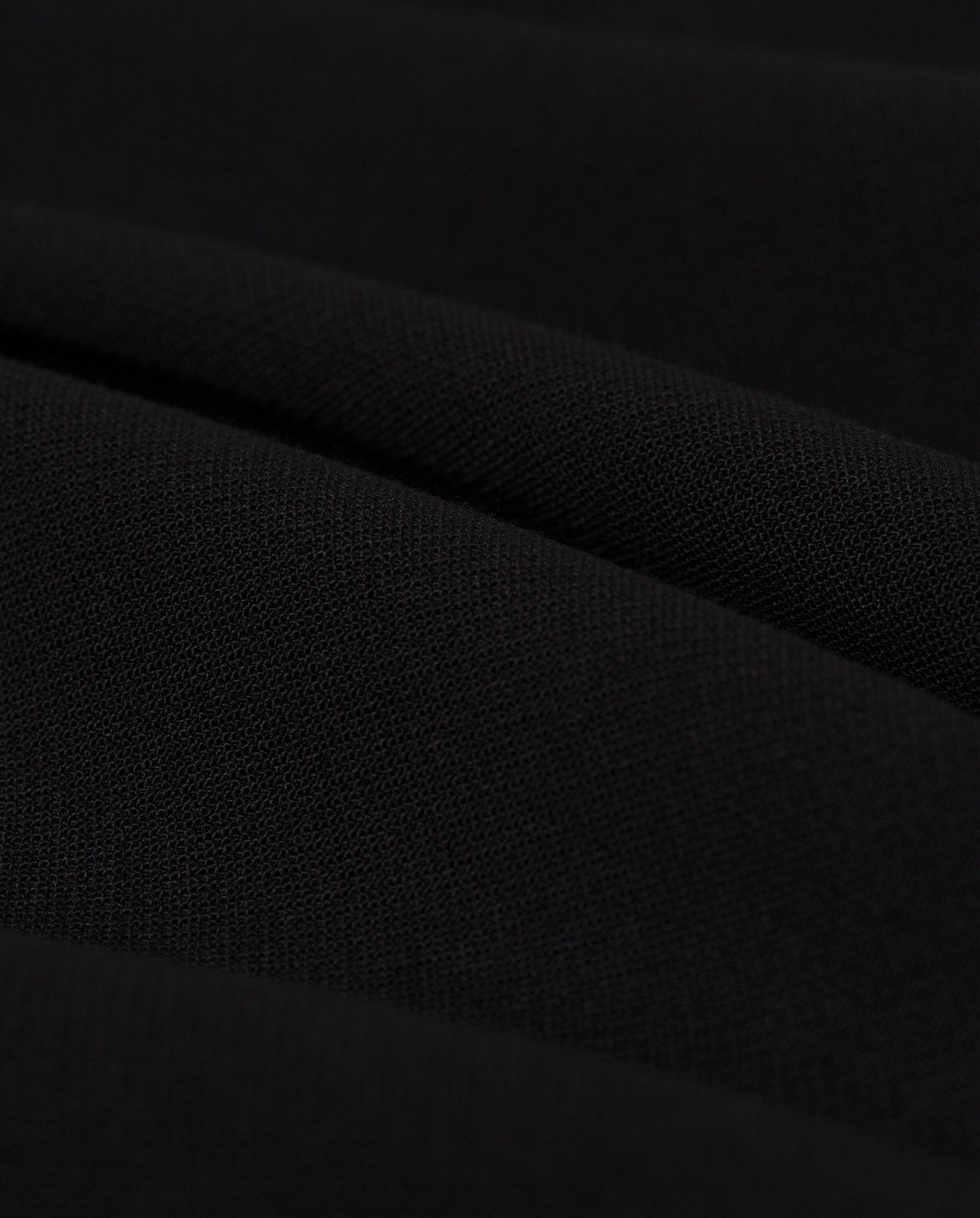 Close-up of the black fabric with soft folds and subtle texture, ideal for pairing with IVY OAKs PIPPA Pants.