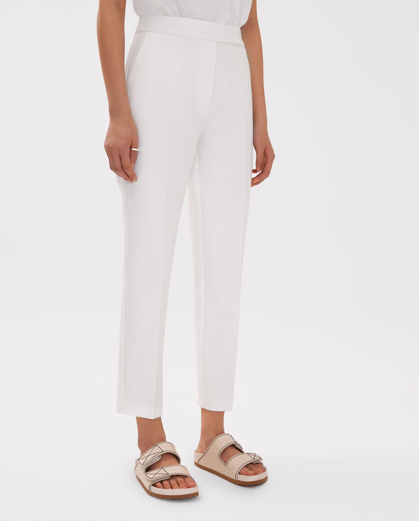 Model wears IVY OAK Ankle Length PIPPA Pants with pockets and beige sandals, posing against a plain white background.