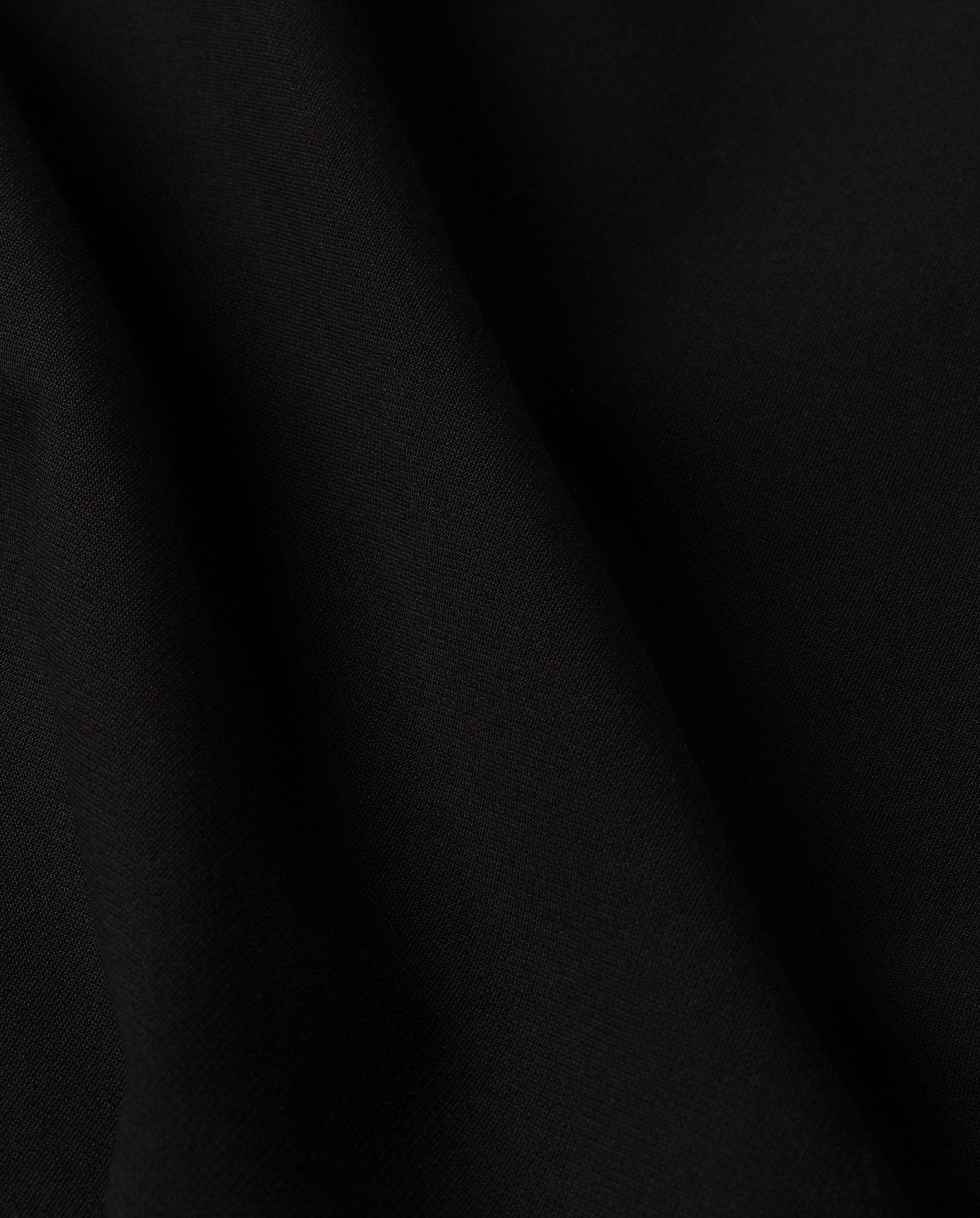 Close-up of black fabric with soft folds and a smooth, matte texture—ideal for the IVY OAK MAREN Dress or an elegant off-shoulder look.