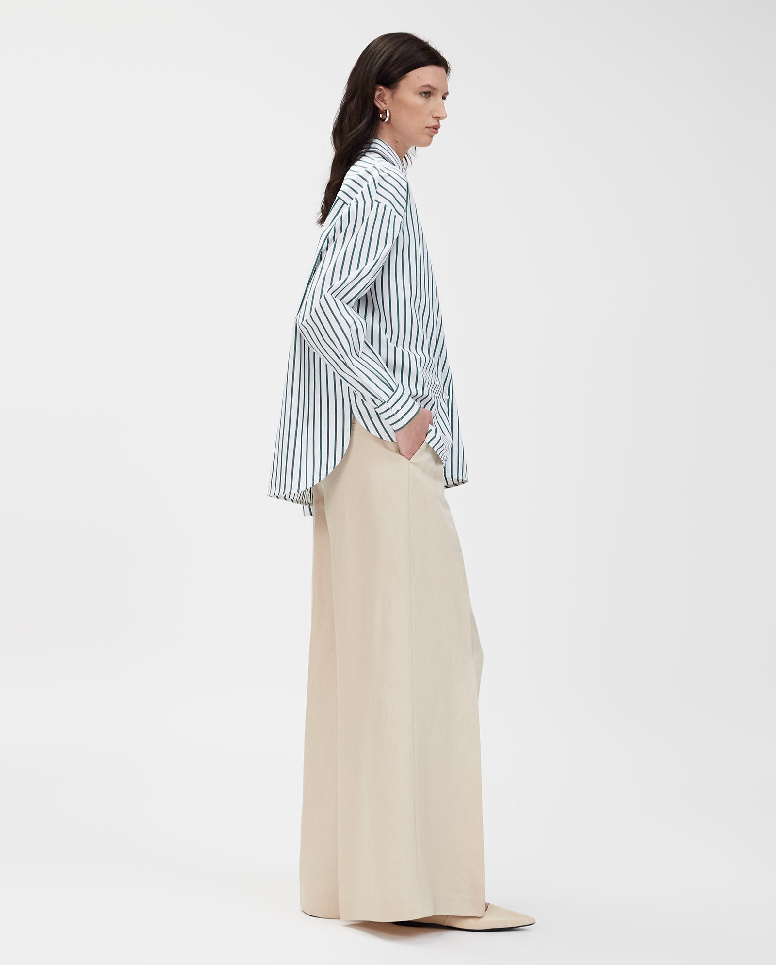 Woman wearing the IVY OAK BETHANY LILLY Blouse with a boxy cut and wide-leg beige pants, standing sideways against a plain white background.