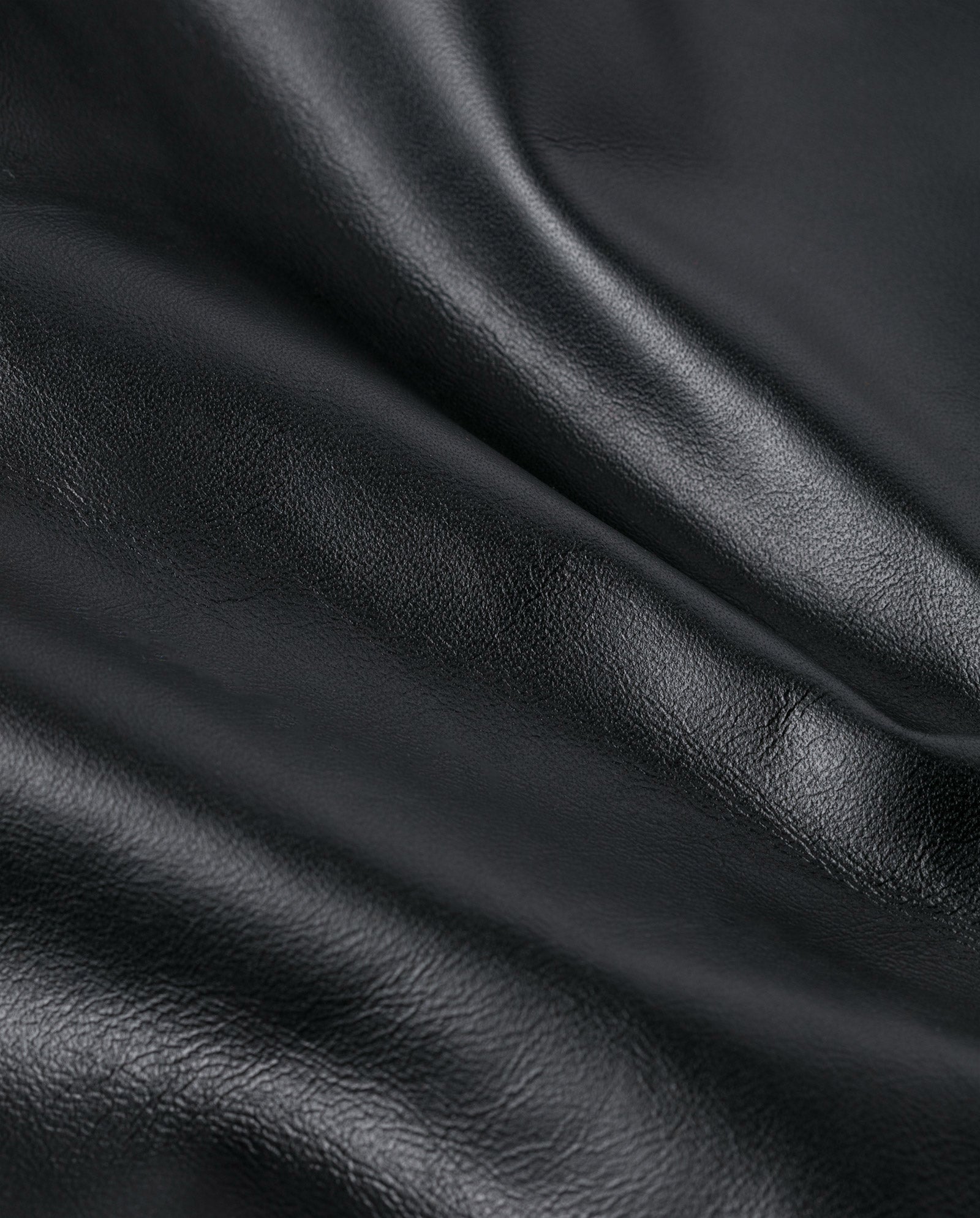Close-up of smooth, black chrome-free leather from IVY OAK’s LAUREEN skirt, showing soft natural folds and a subtle sheen—ideal for creating luxe midi looks.