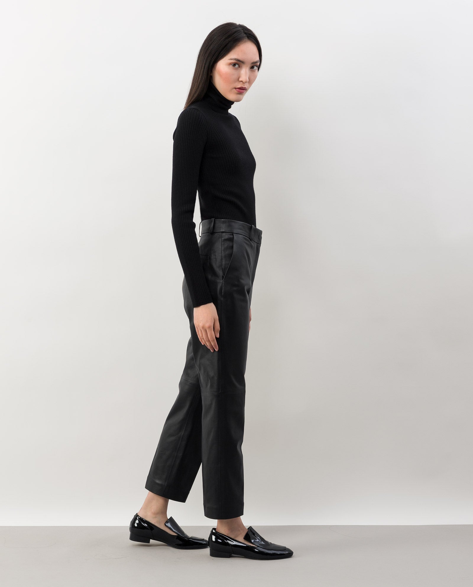 A woman in a black turtleneck, IVY OAK LAURA Leather Trousers (slim fit, chrome-free), and black loafers stands against a plain white background.