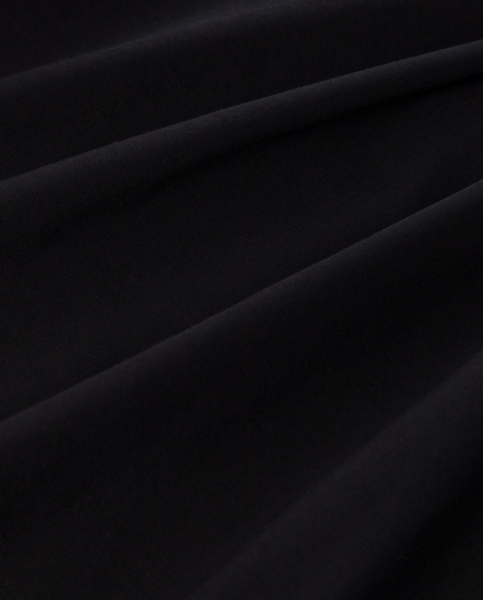 Close-up of the KYLA T-Shirt by IVY OAK: smooth black organic cotton fabric with gentle folds and a soft, subtle texture—ideal for a classic basic tee.